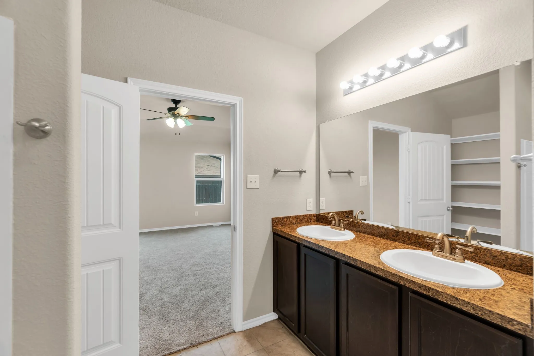 Bathroom featuring tile flooring, dual sinks, ceiling fan, and large vanity
