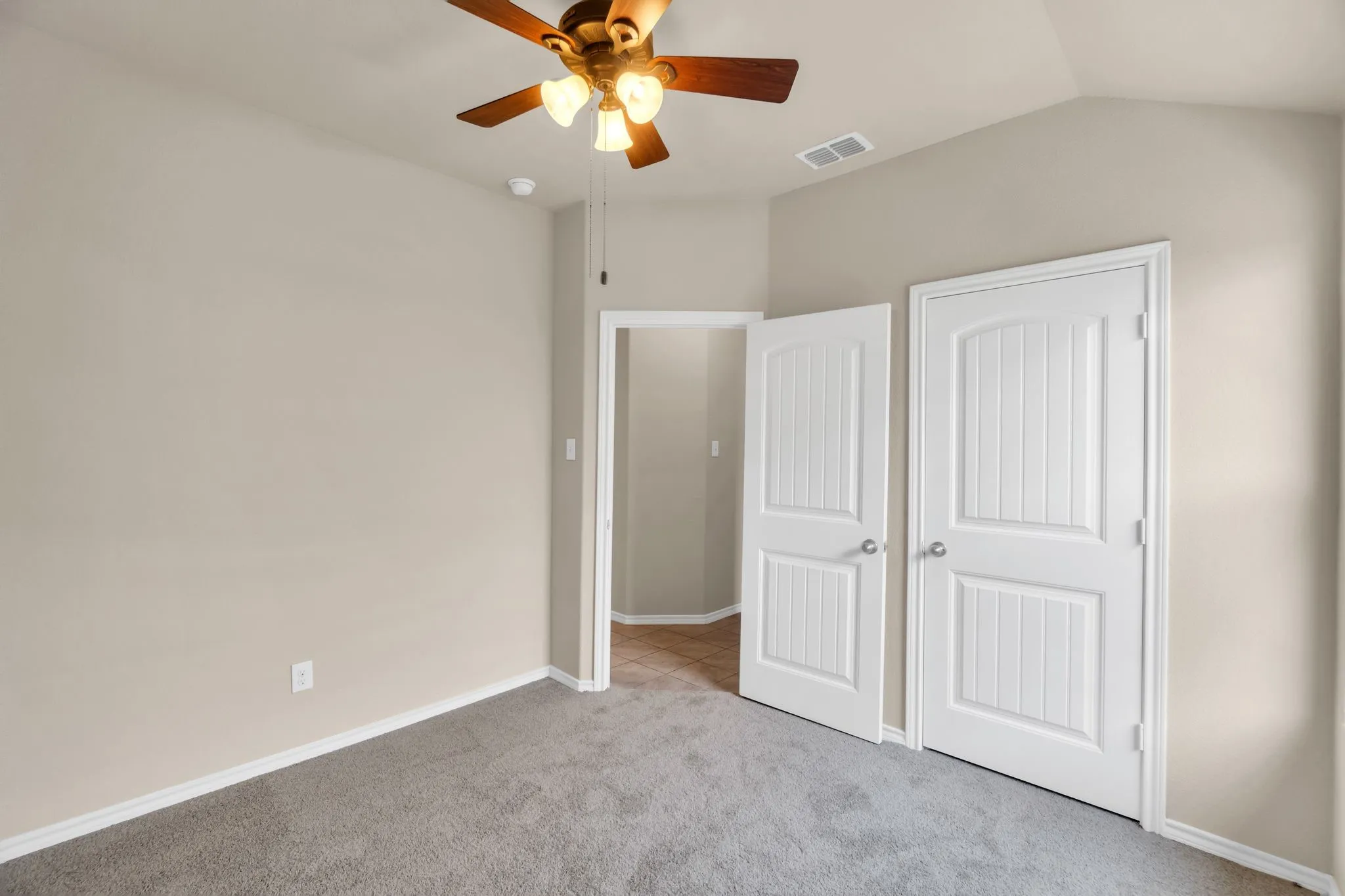 Unfurnished bedroom featuring a closet, ceiling fan, vaulted ceiling, and light colored carpet