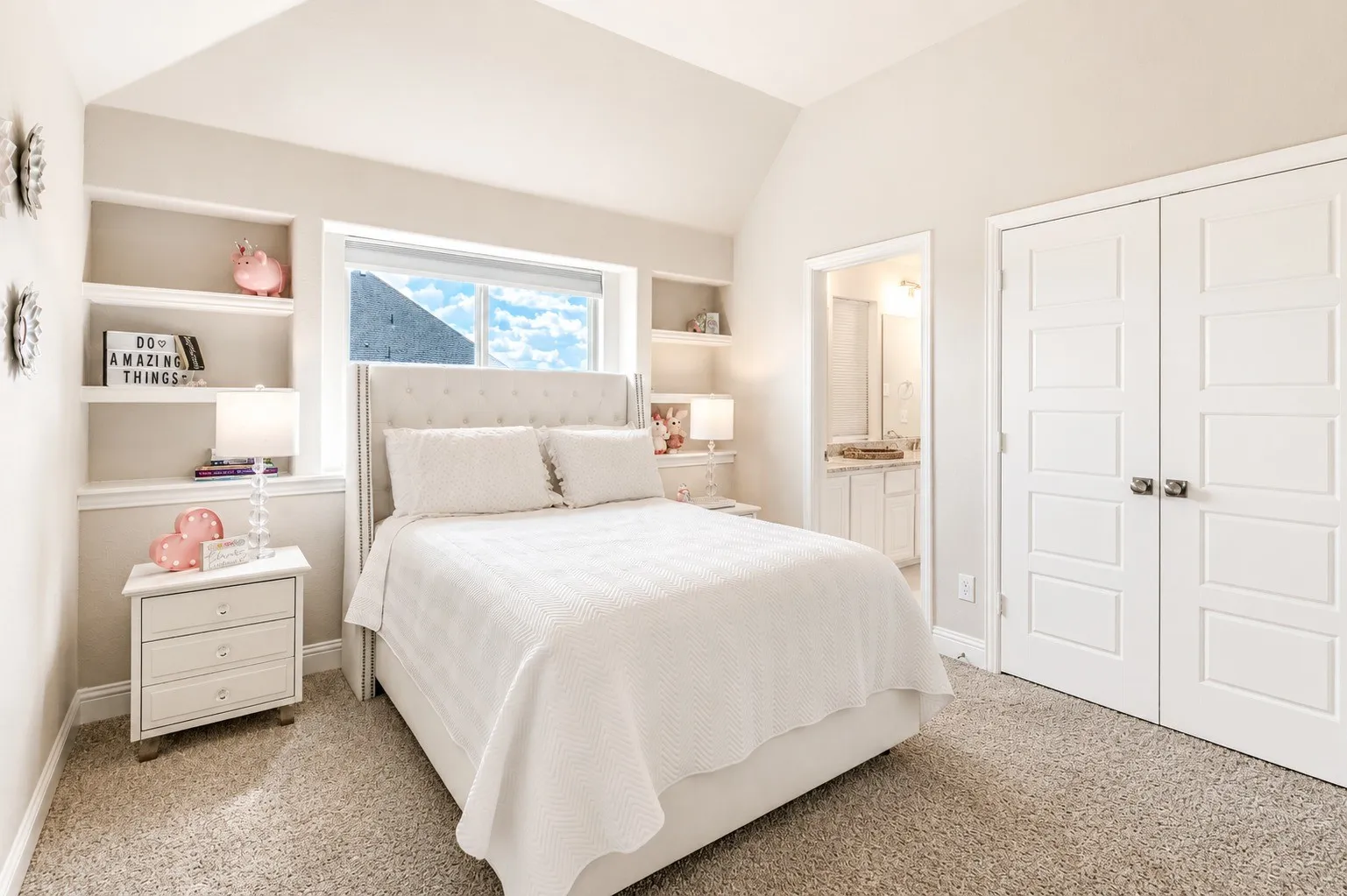 Carpeted sleeping area featuring a vaulted ceiling and built-in shelving