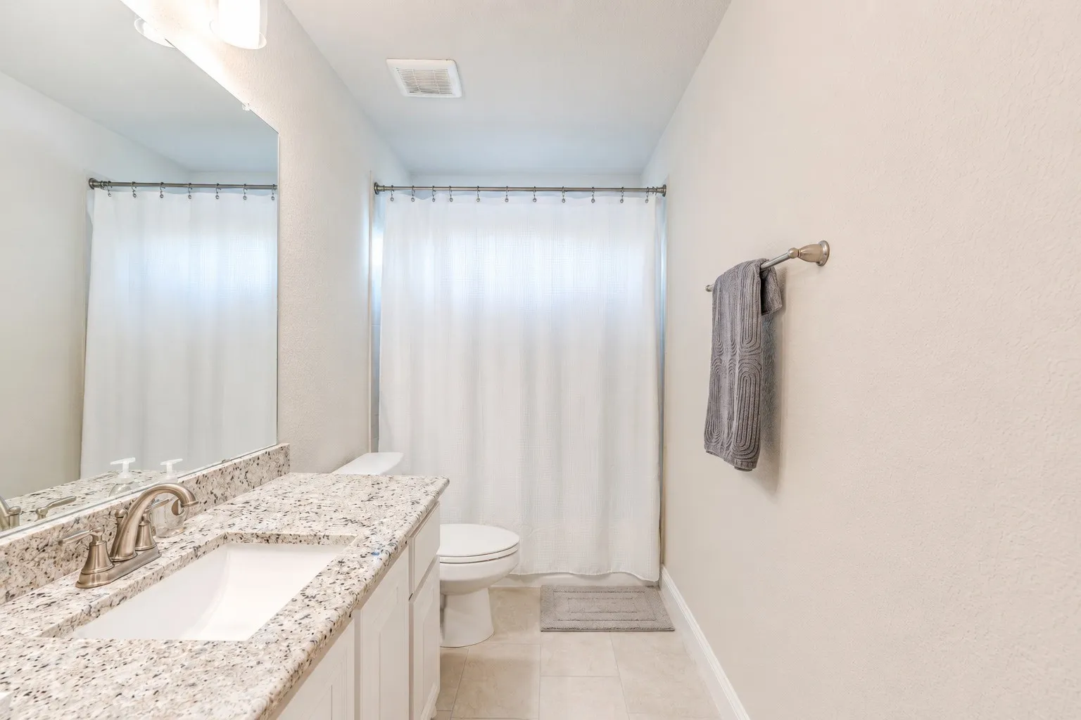 Bathroom featuring a vanity with a white countertop and integrated sink, brushed nickel faucet, and overhead bar lighting