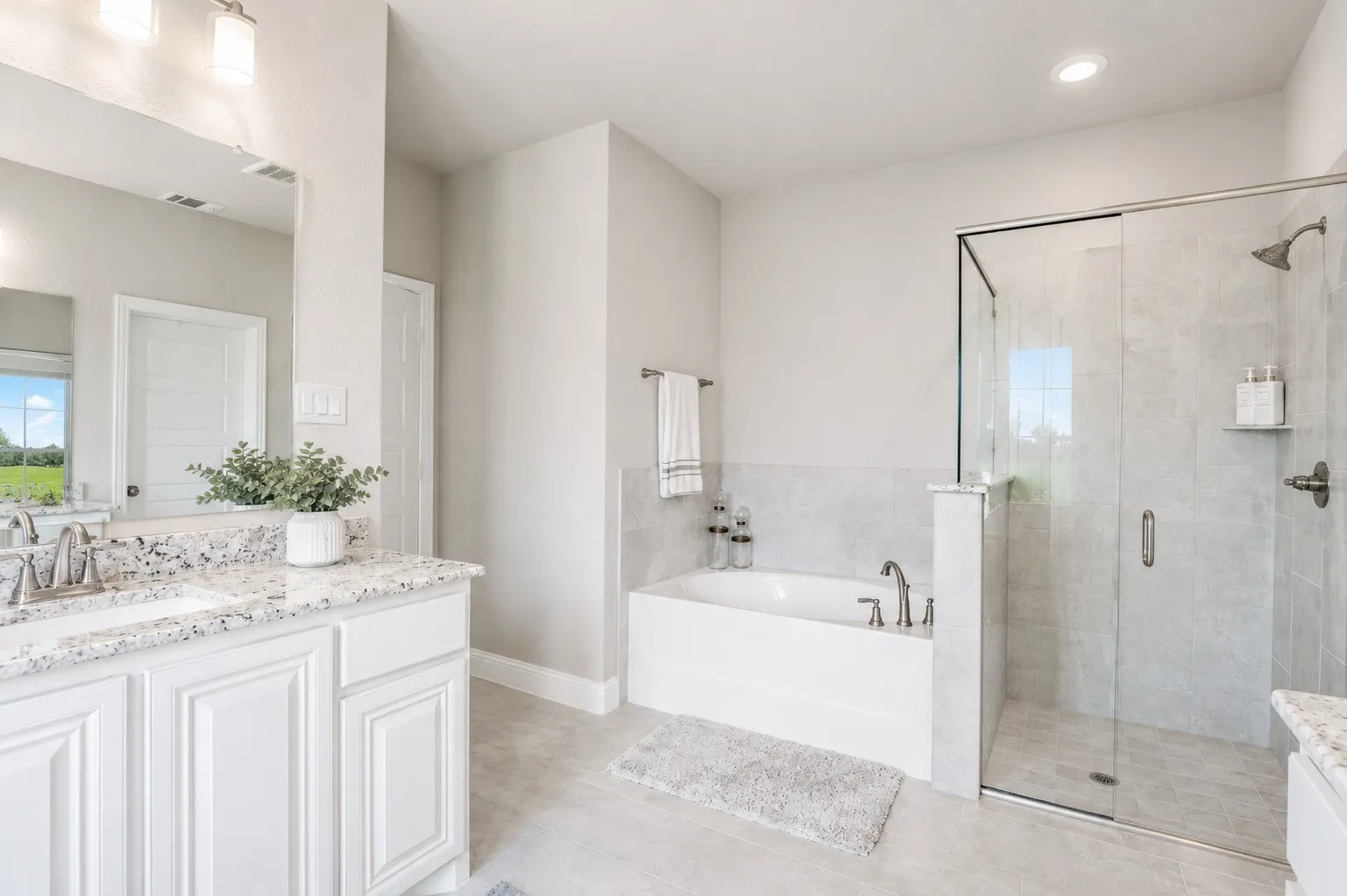 Bathroom featuring a dual-sink vanity with a speckled countertop, white cabinetry, a built-in soaking tub, and a glass-enclosed shower with tile surround