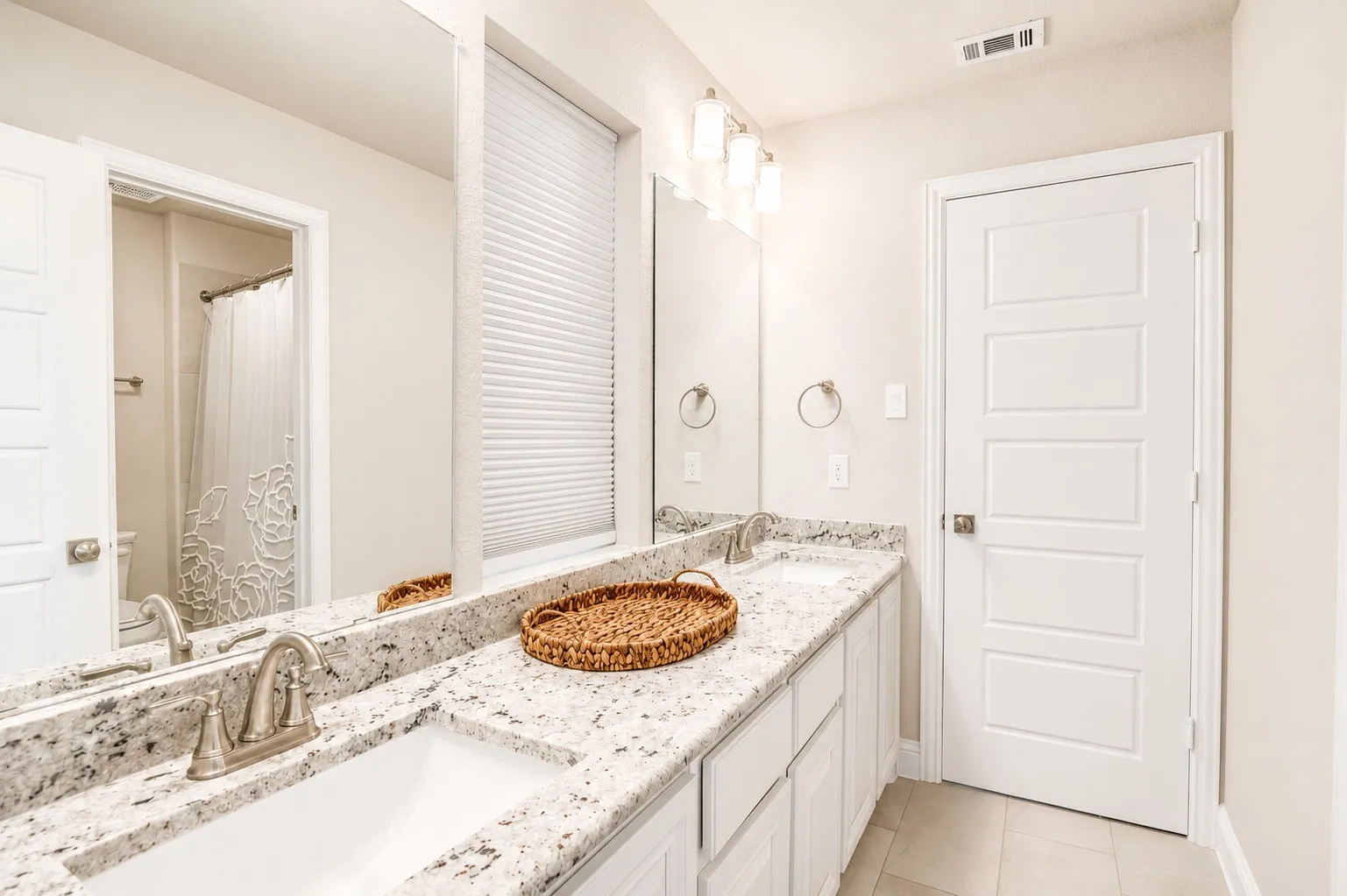Double vanity with integrated sinks, speckled stone countertops, and brushed nickel fixtures