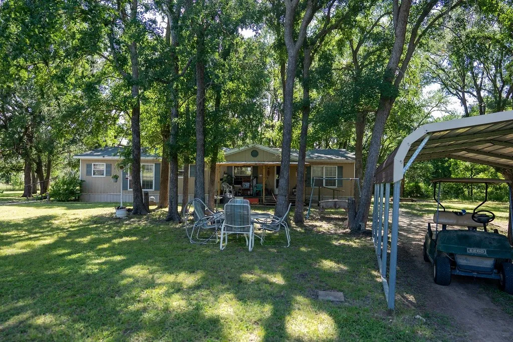 Expansive green lawn with mature trees providing extensive shade