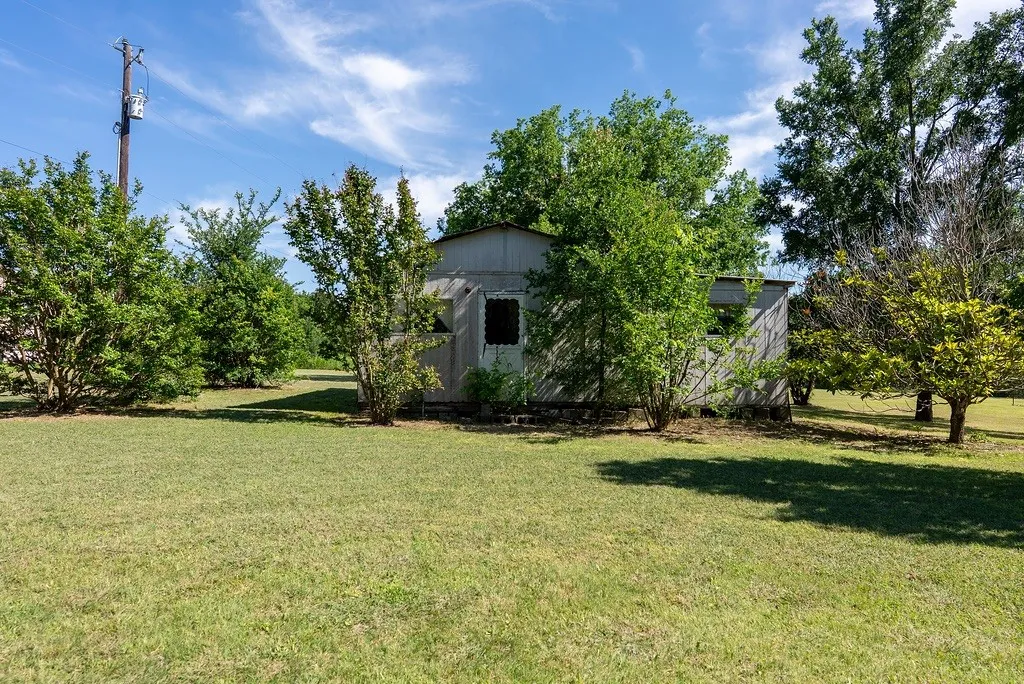 Expansive grassy area with a freestanding structure featuring a corrugated metal exterior