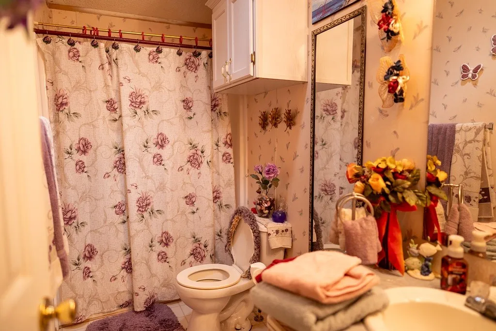 Bathroom featuring a floral-patterned shower curtain and coordinating wallpaper