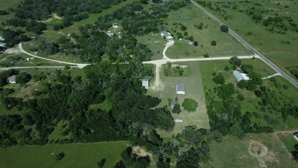 Expansive rural landscape featuring a mix of mature trees, open grassy areas, and a visible roadway