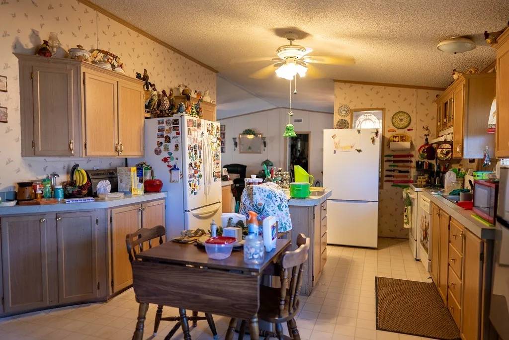 Kitchen featuring light wood cabinetry, white appliances, and a central island with an integrated dining table