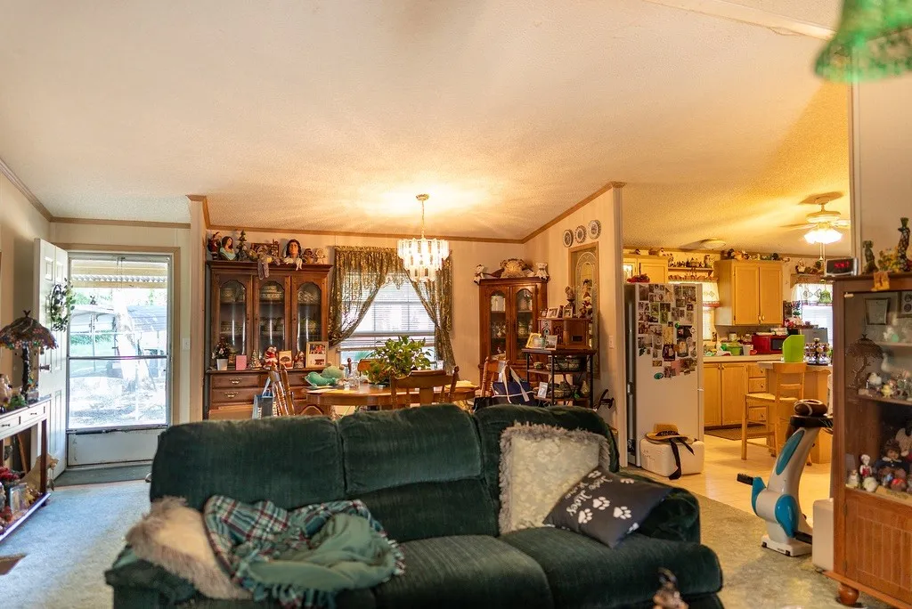 Living area featuring carpet flooring, crown molding, and a chandelier lighting fixture