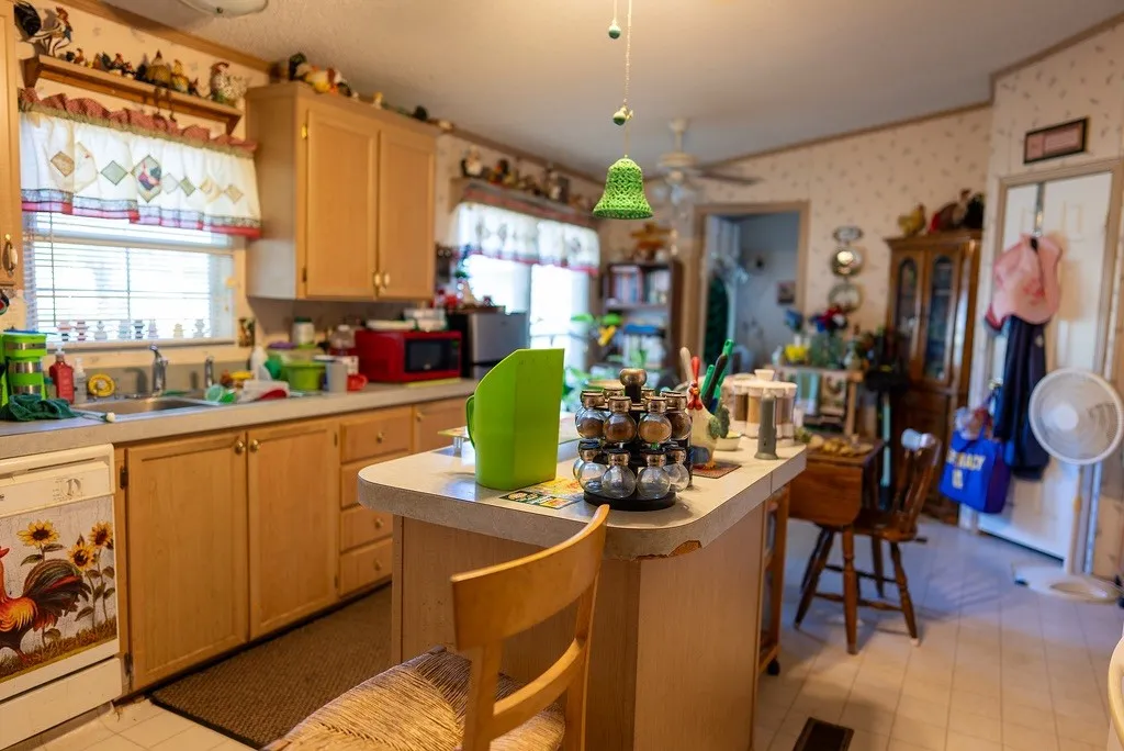 Kitchen featuring light wood cabinetry, a central island with a light-toned countertop, and a window above the sink