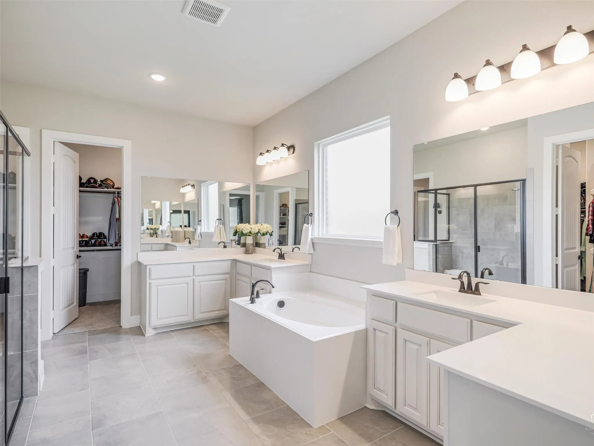 Luxurious primary ensuite at 544 Majors Road featuring a deep soaking tub, separate shower with built-in seat, and his-and-her closets in Van Alstyne, TX.