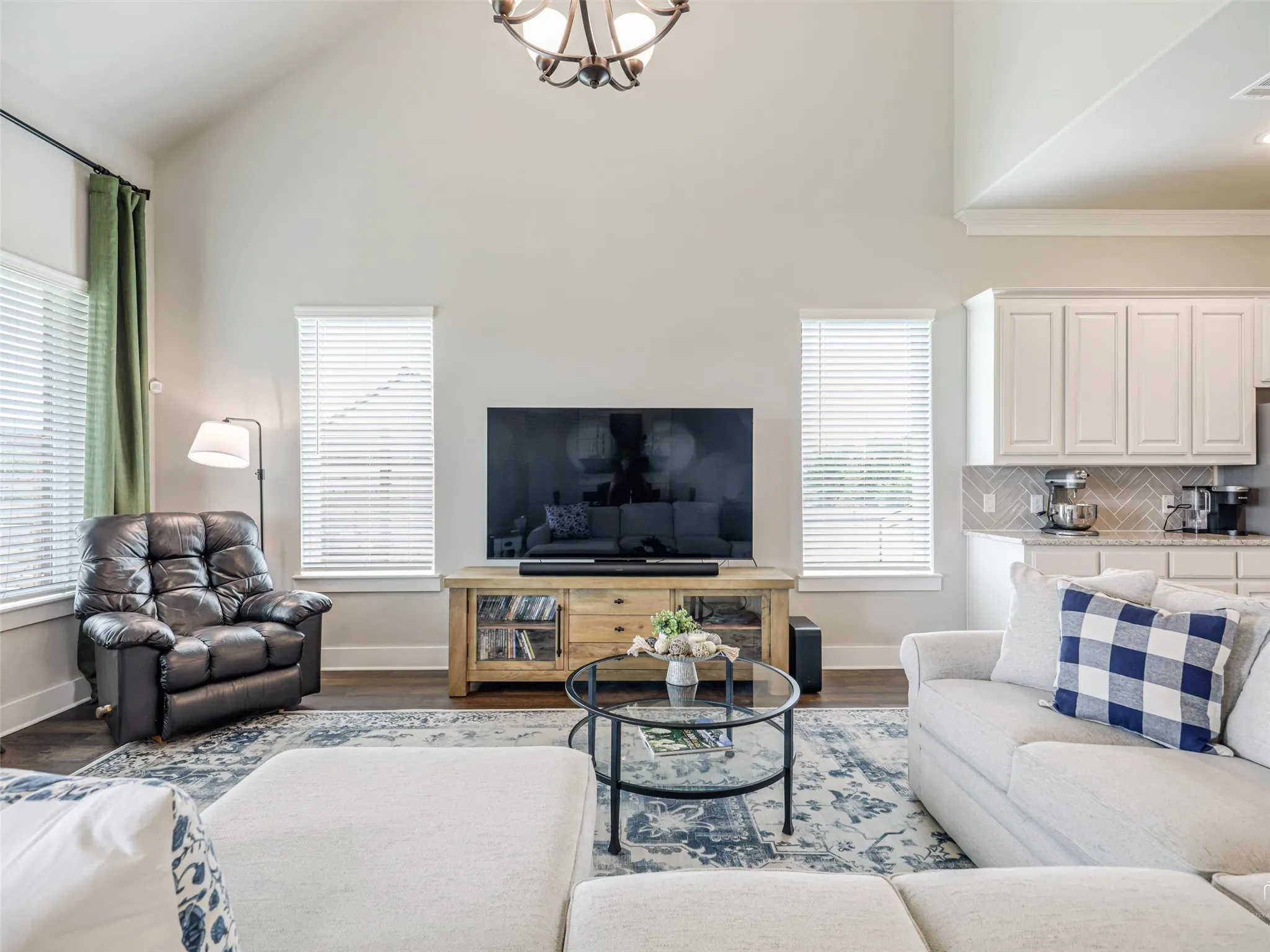 dditional view of the open-concept living area at 544 Majors Road, featuring soaring two-story ceilings, a statement fireplace, wood floors, and seamless flow into the chef's kitchen with its 12-foot quartz island in Van Alstyne, Texas.