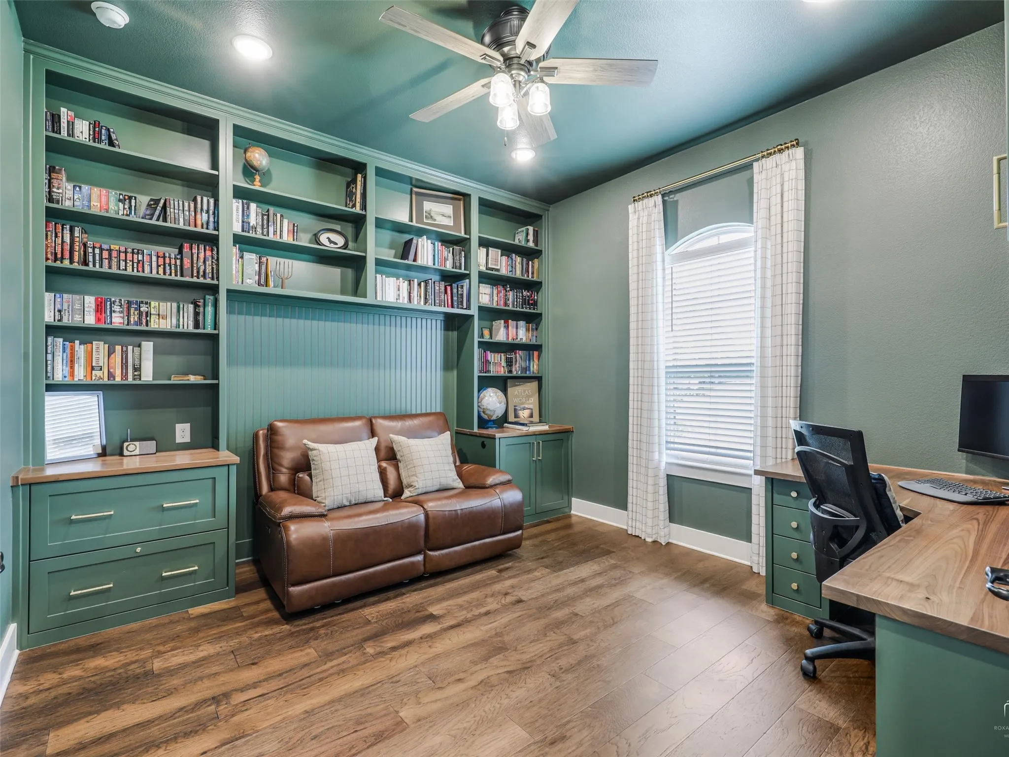 Private main level home office at 544 Majors Road in Van Alstyne Texas featuring custom floor to ceiling built in bookshelves matching desk rich wood flooring and abundant natural light Ideal space for working from home or private library study