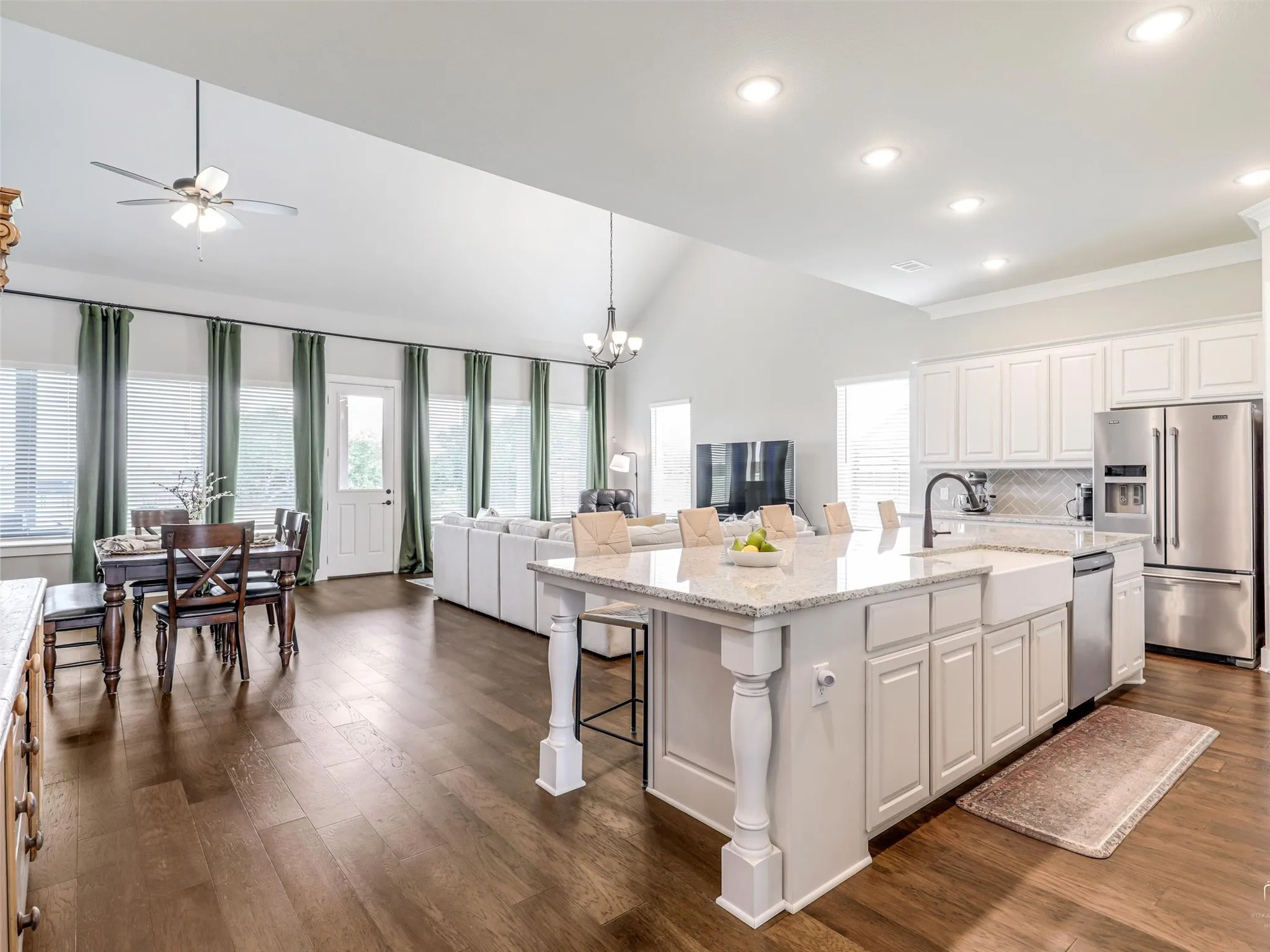 Seamless open flow from the main living area into the chef's dream kitchen at 544 Majors Road, defined by wood floors, soaring ceilings, and natural light throughout this Van Alstyne estate.
