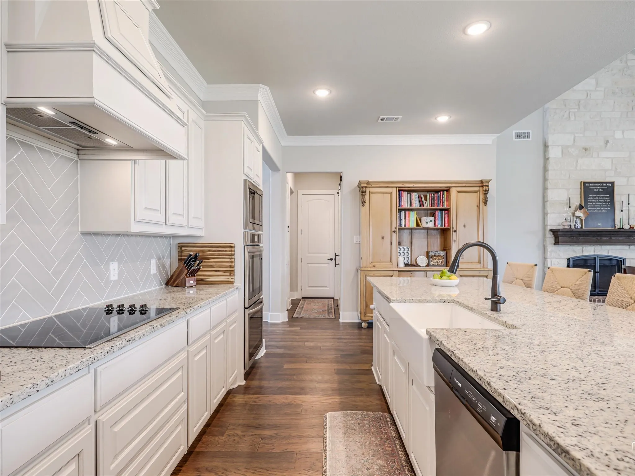 The heart of 544 Majors Road in Van Alstyne, TX: a chef's dream kitchen featuring a magnificent 12-foot quartz island, double ovens, and a farmhouse apron sink.