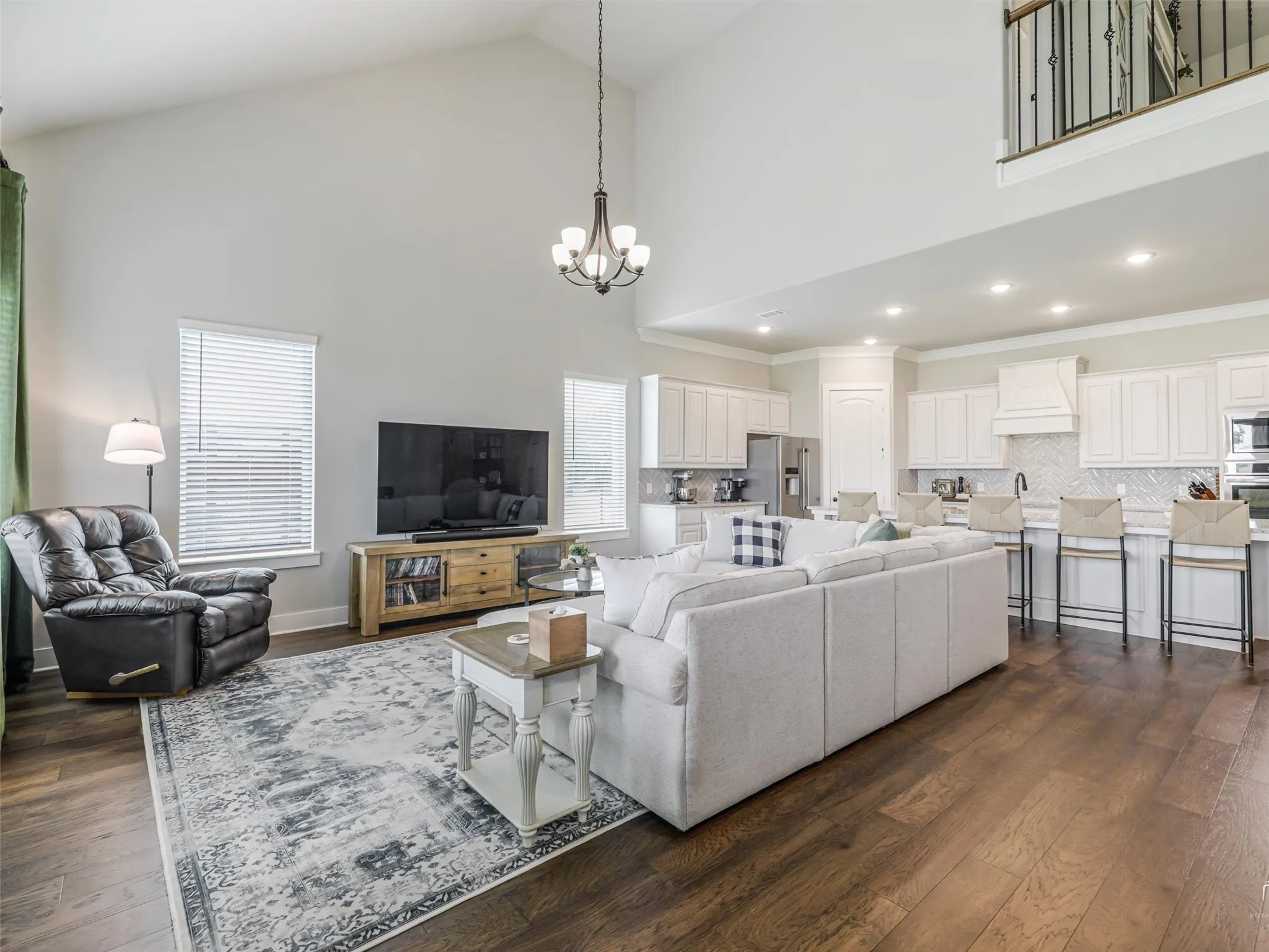 Spacious open-concept living area at 544 Majors Road featuring rich wood floors, soaring two-story ceilings, and walls of windows in Van Alstyne, Texas.