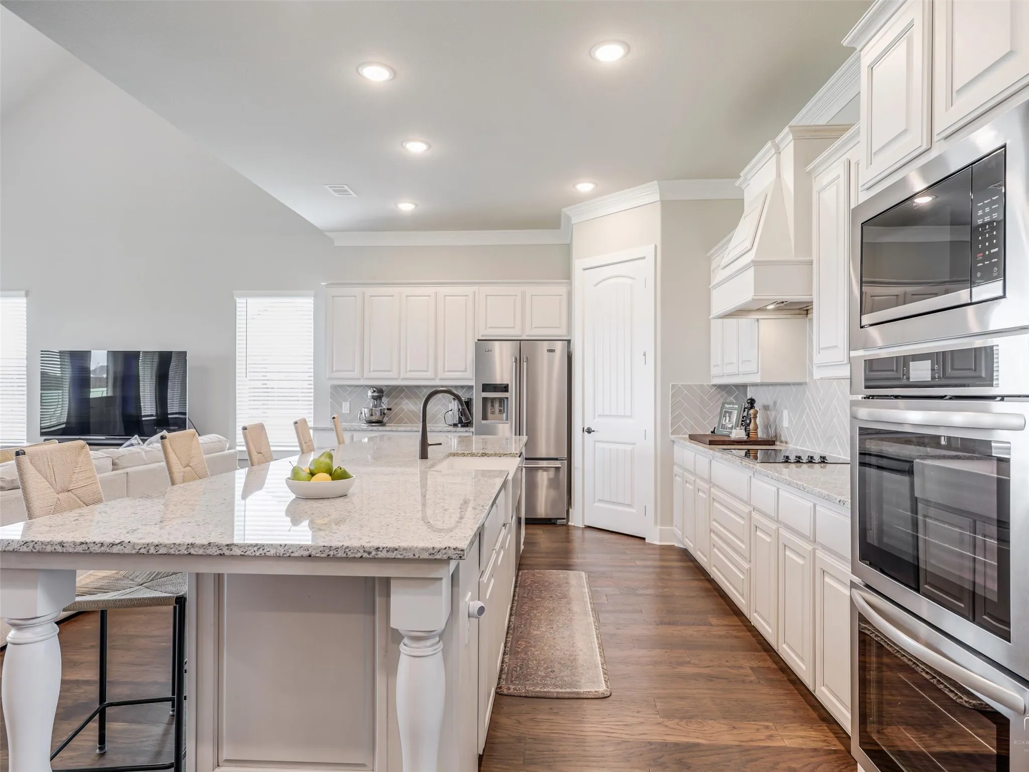 Gourmet kitchen at 544 Majors Road in Van Alstyne Texas featuring a massive 12 foot quartz island stainless steel double ovens farmhouse apron sink built in microwave white cabinetry walk in pantry and plumbed for a propane cooktop Perfect space for entertaining and culinary creation