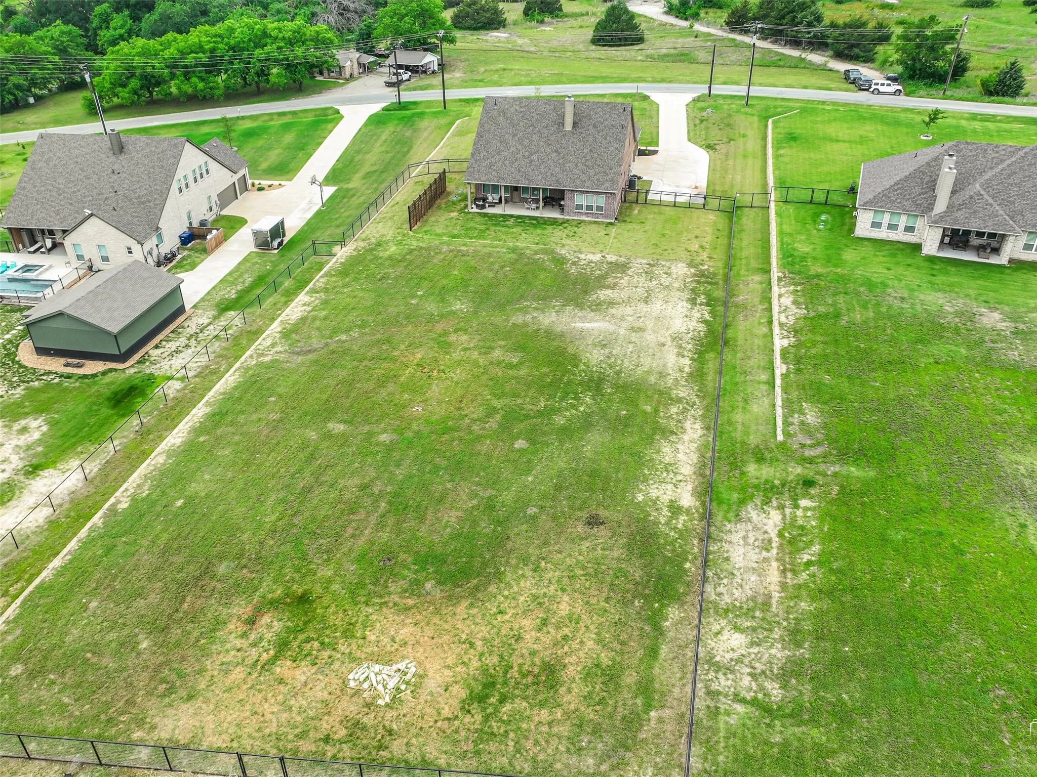 Stunning aerial view of 544 Majors Road showcasing the full 1-acre pipe-fenced lot, oversized 3.5-car garage, covered back porch, and surrounding Van Alstyne, Texas acreage with room for a future pool.