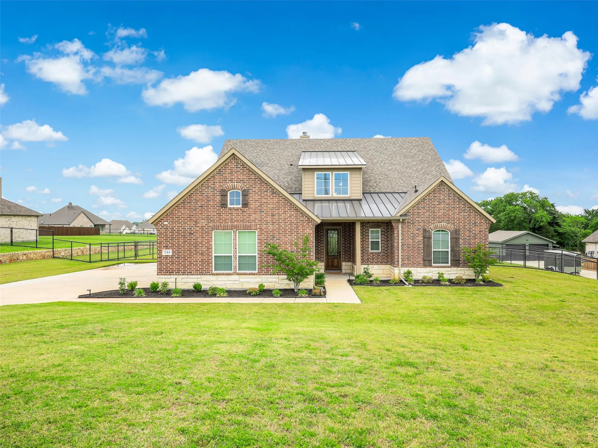 Grand curb appeal at 544 Majors Road, Van Alstyne, TX, with mature landscaping, an expansive driveway, and an oversized 3.5-car garage on a sprawling 1-acre pipe-fenced lot.