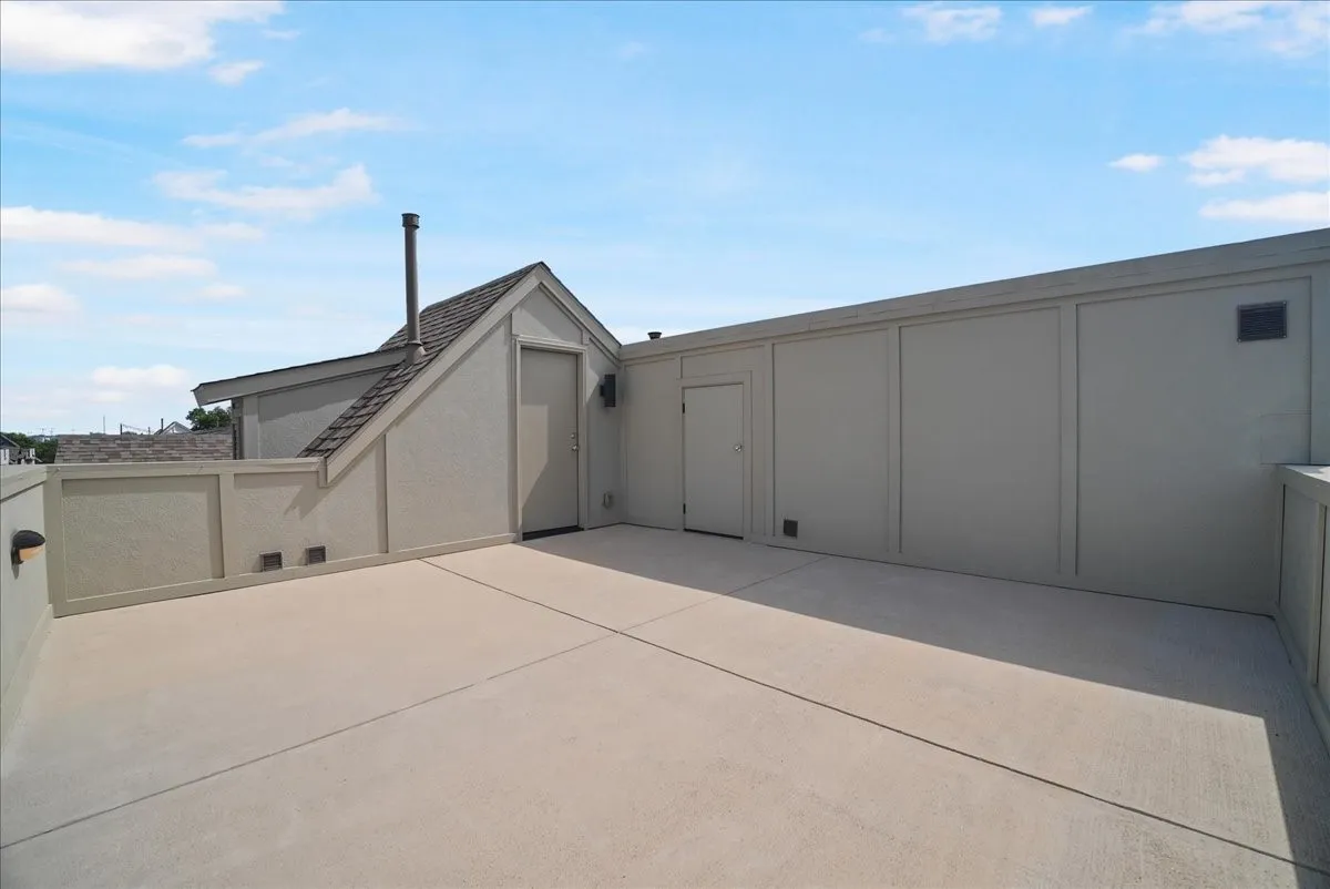 Expansive rooftop deck featuring a stucco exterior, integrated lighting, and multiple access doors