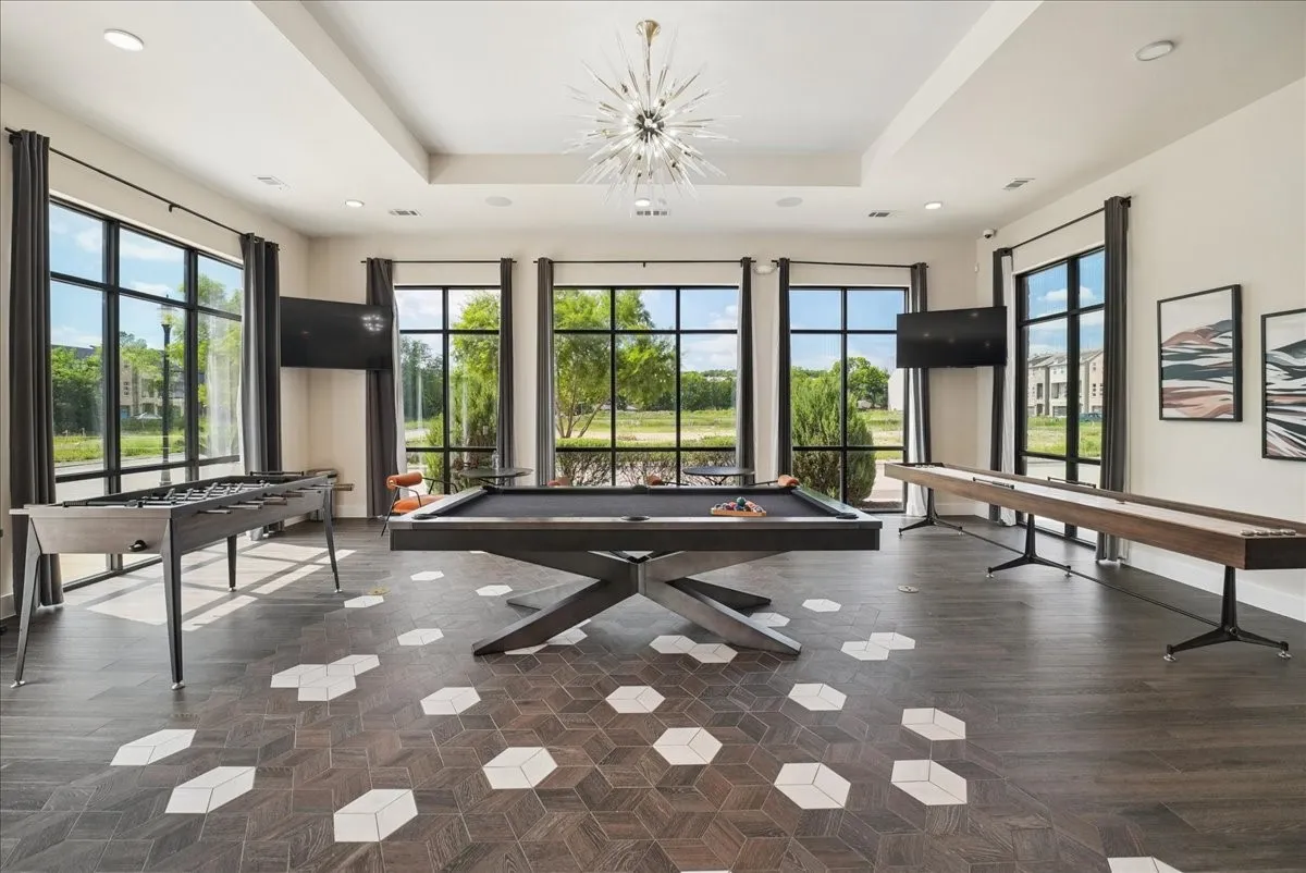 Spacious recreation room featuring dark wood-finish flooring with geometric tile inlays