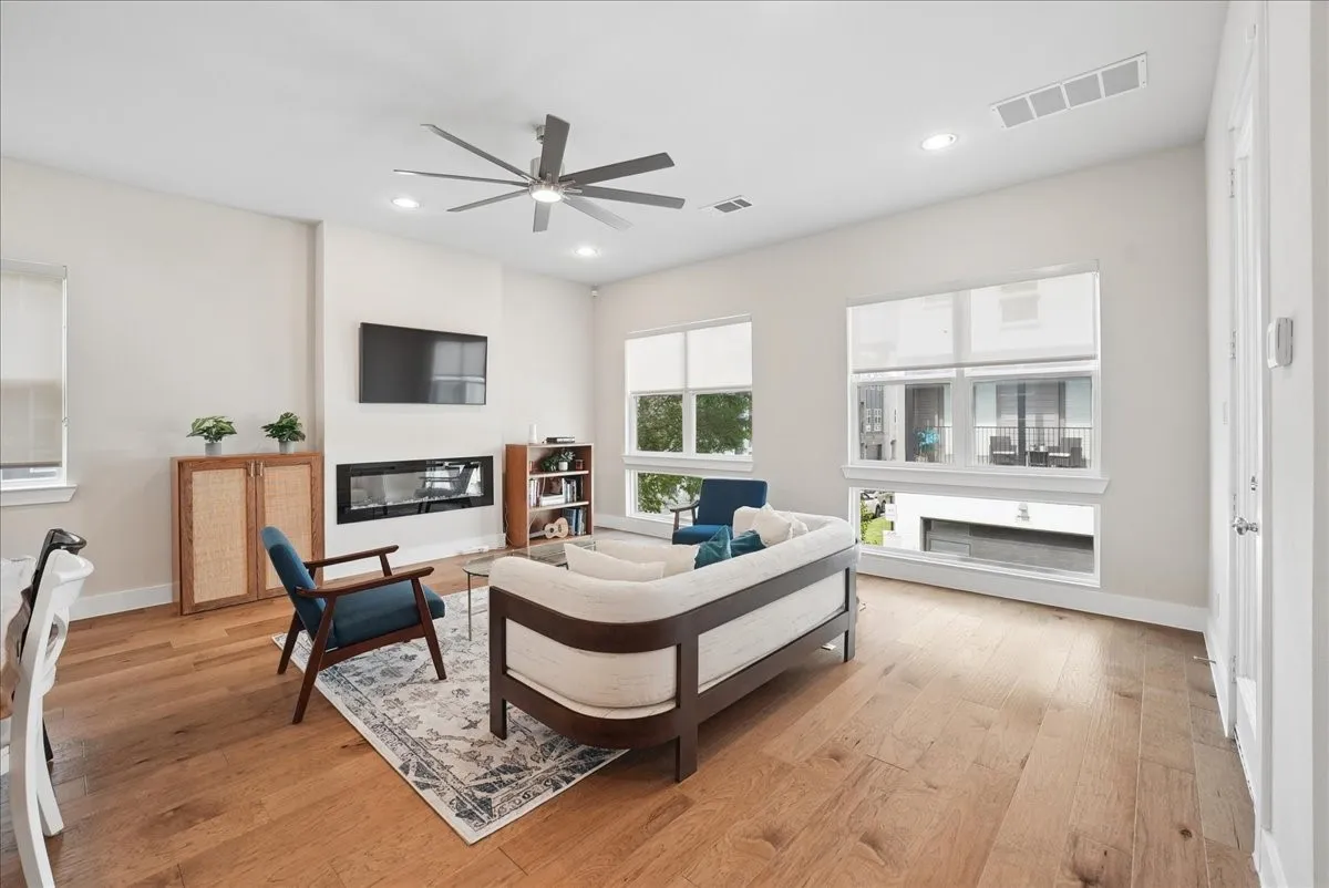 Spacious living area featuring light wood-finish flooring, recessed lighting, and a modern linear fireplace