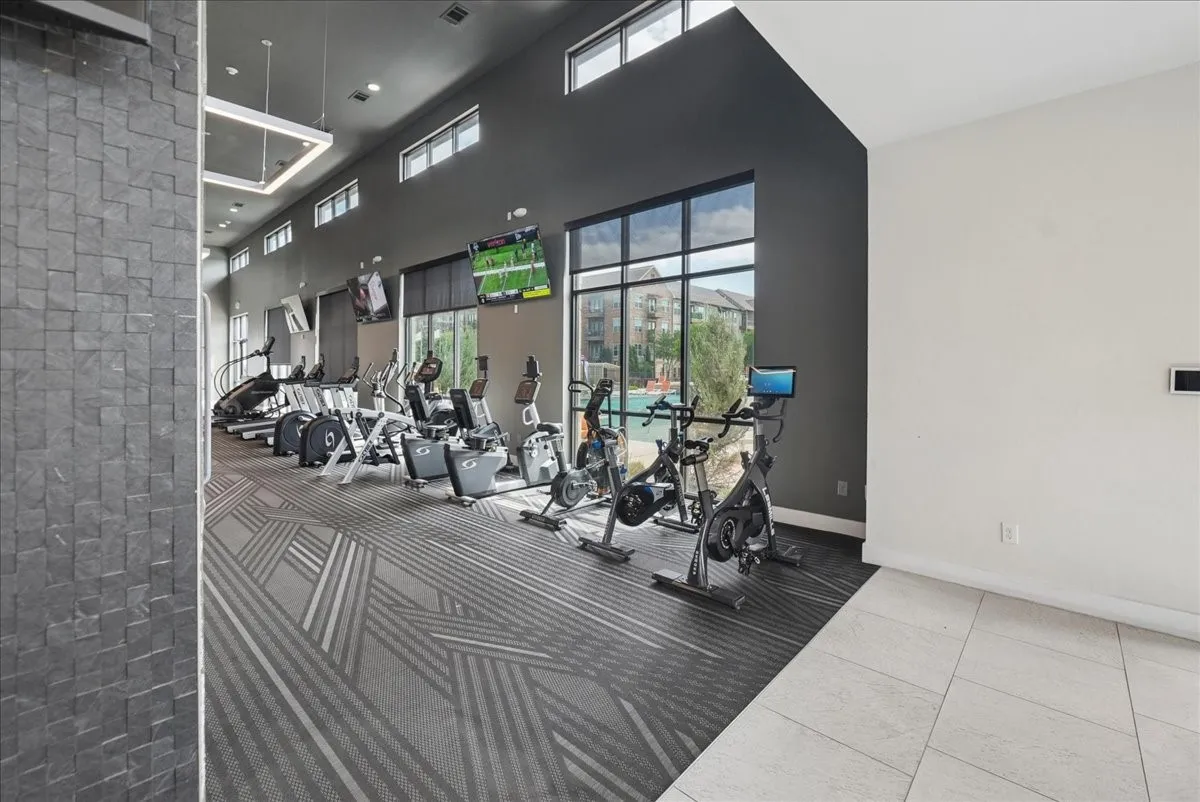 Fitness center featuring a textured accent wall, contemporary patterned carpet, and floor-to-ceiling windows