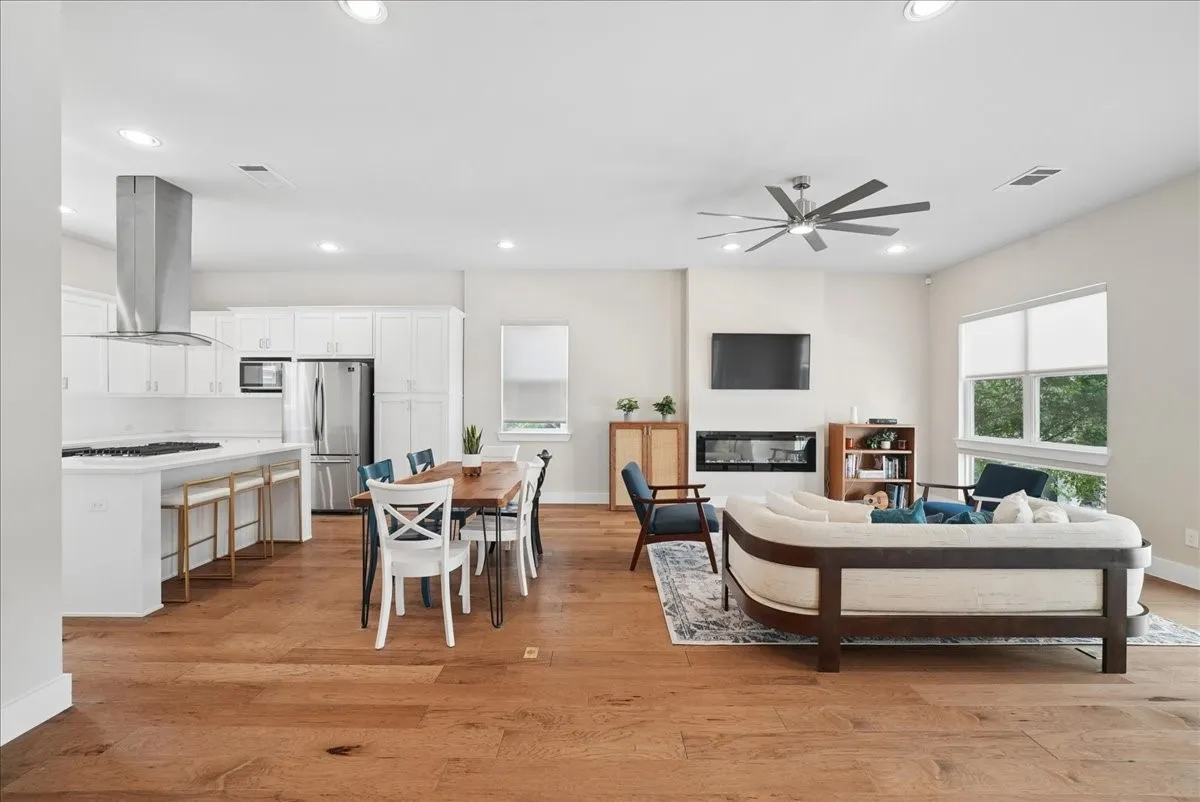 Open-concept living space featuring wood-finish flooring, recessed lighting, and high ceilings