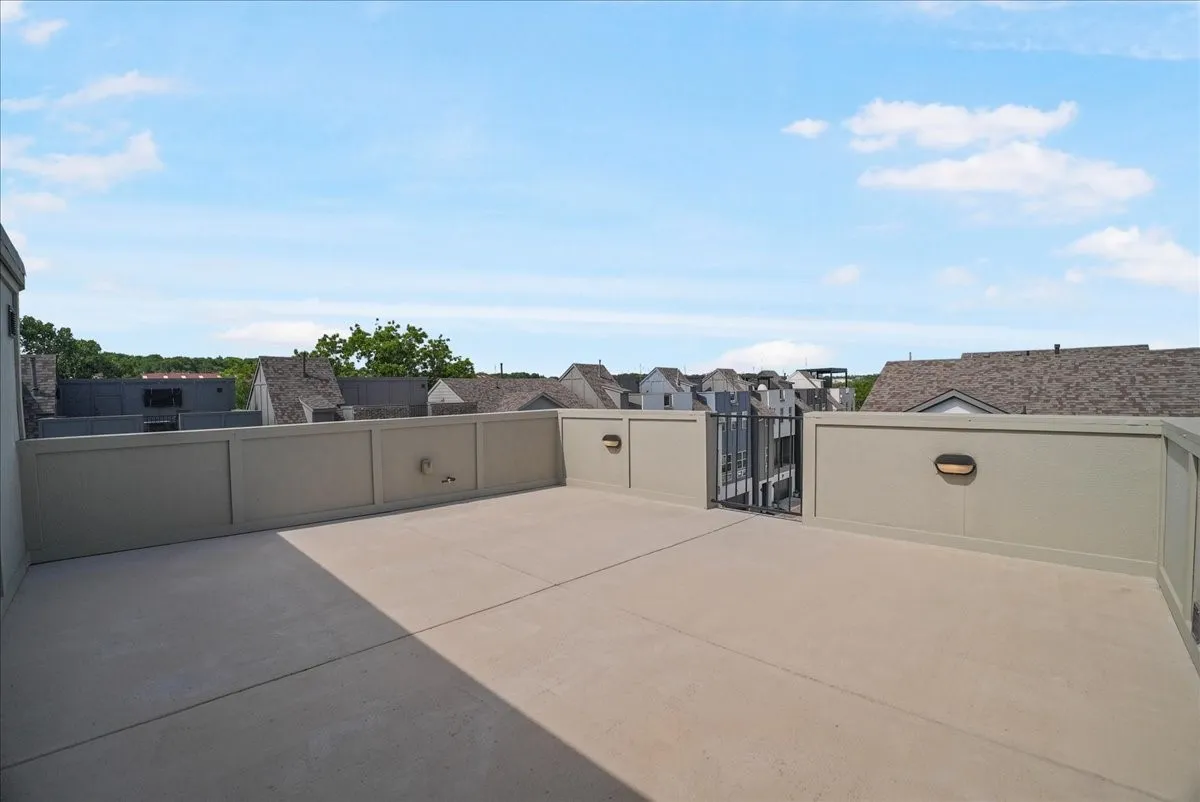 Expansive rooftop deck featuring a concrete surface, perimeter wall, and built-in exterior lighting