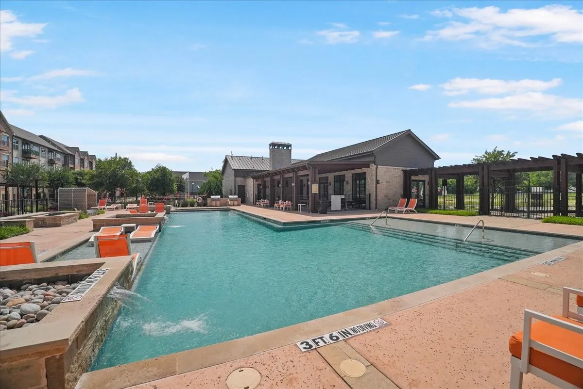 Resort-style swimming pool featuring a shallow entry, integrated lounge seating, and perimeter hardscaping