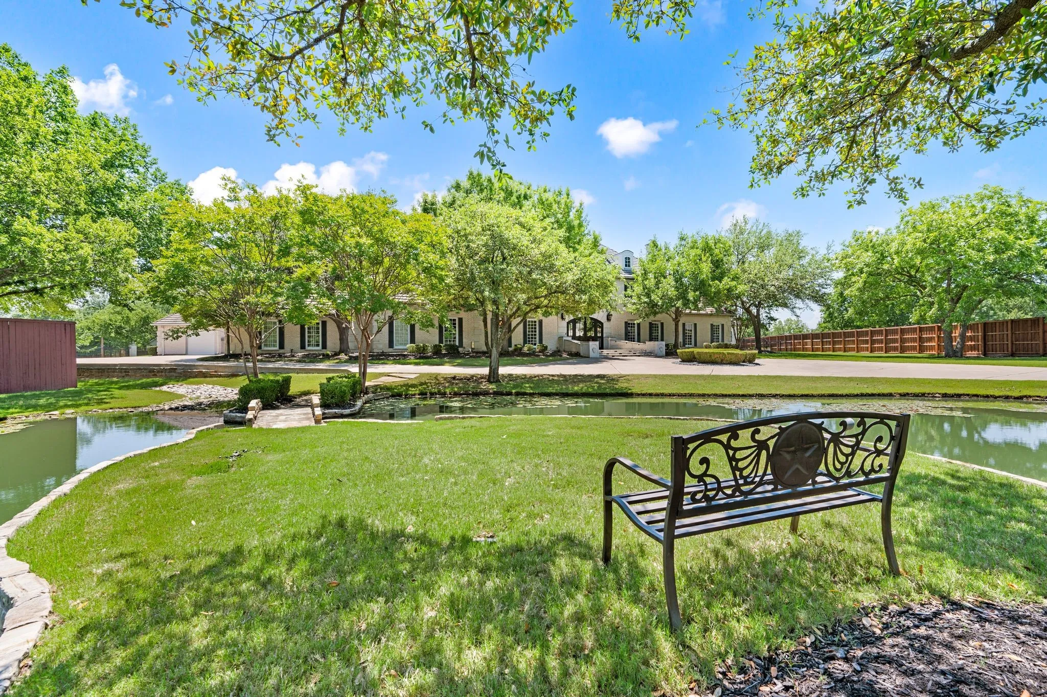 Lush green lawn with a decorative metal bench and a tranquil pond