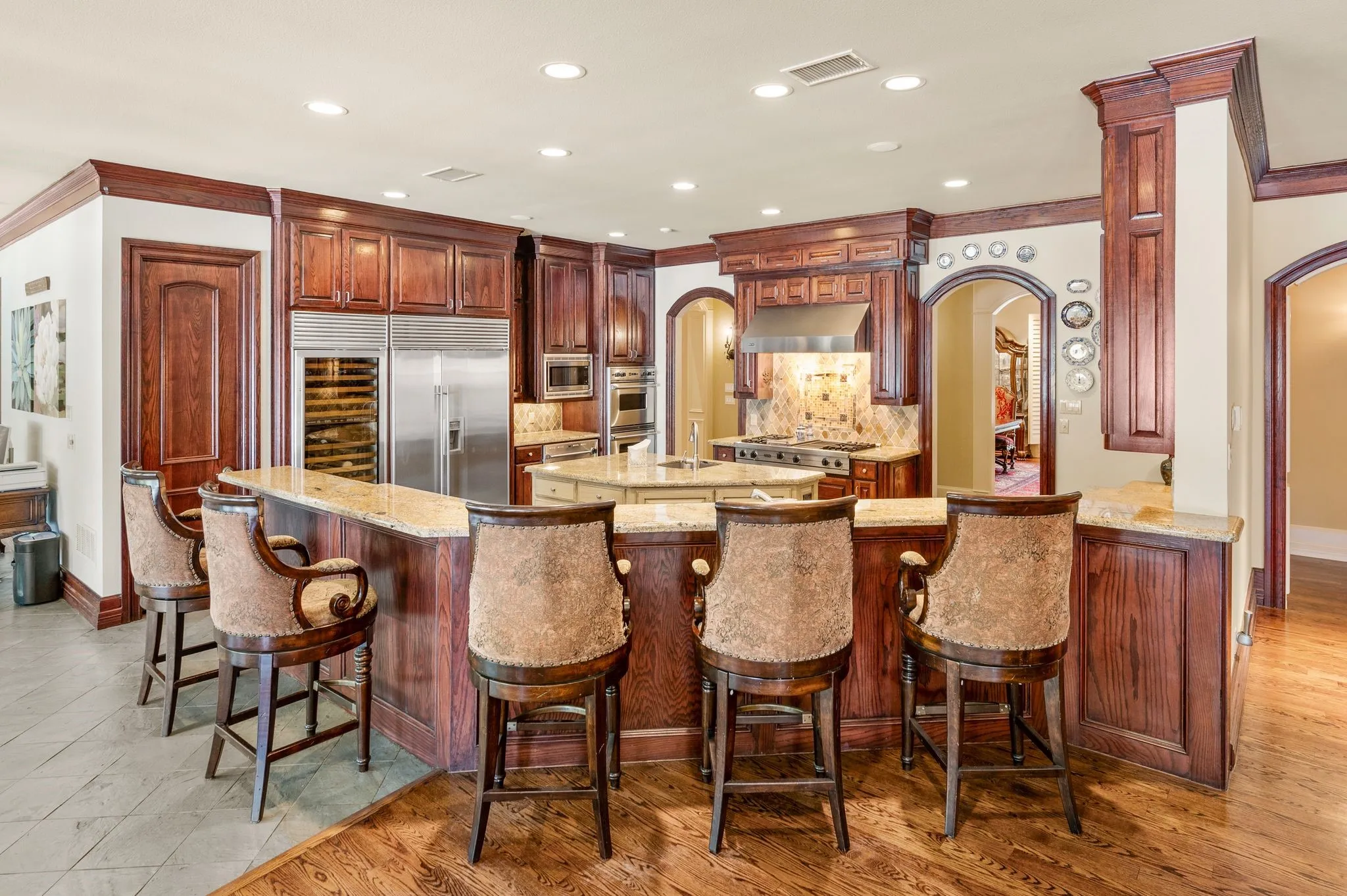 Gourmet kitchen featuring custom wood cabinetry, stainless steel appliances, granite countertops, a large center island, and a separate breakfast bar