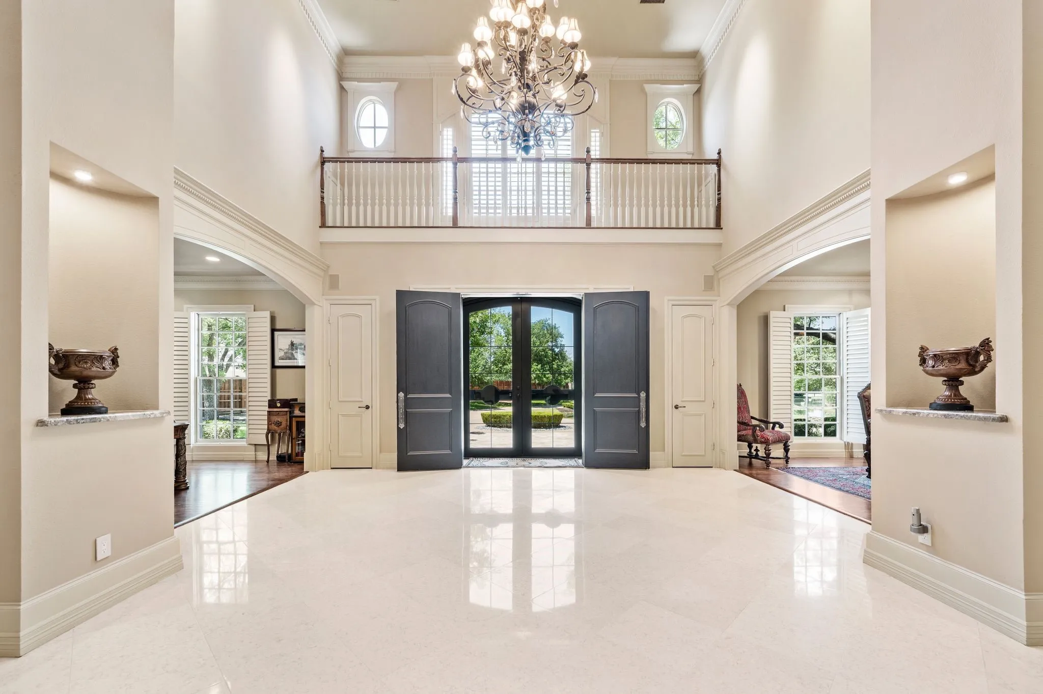 Grand foyer featuring a large chandelier, high ceilings, polished tile flooring, and a second-story balcony