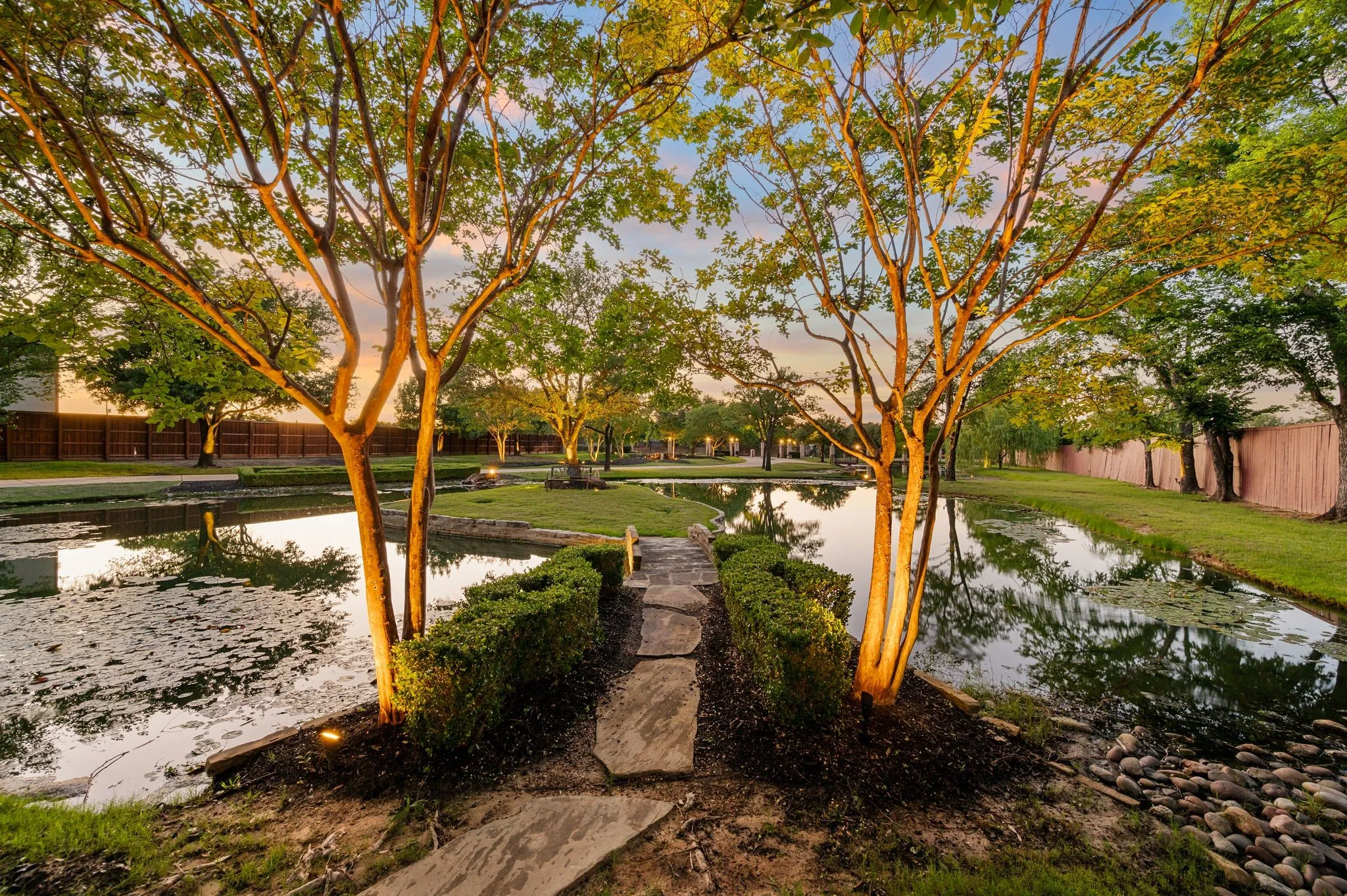 Outdoor pathway featuring flagstone steps, manicured shrubbery, and mature trees with integrated accent lighting