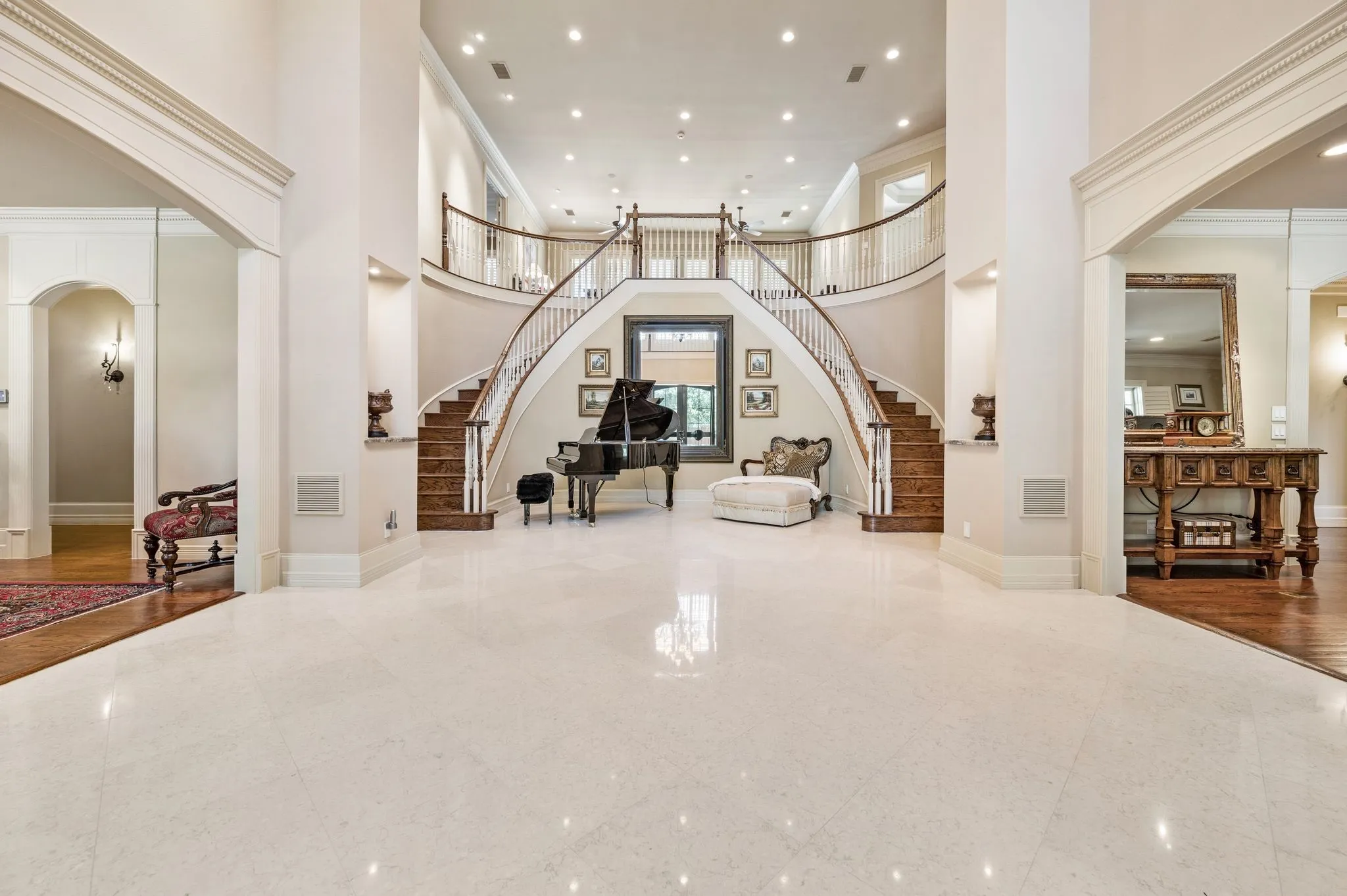 Grand foyer featuring a dual curved staircase with wood treads and white risers