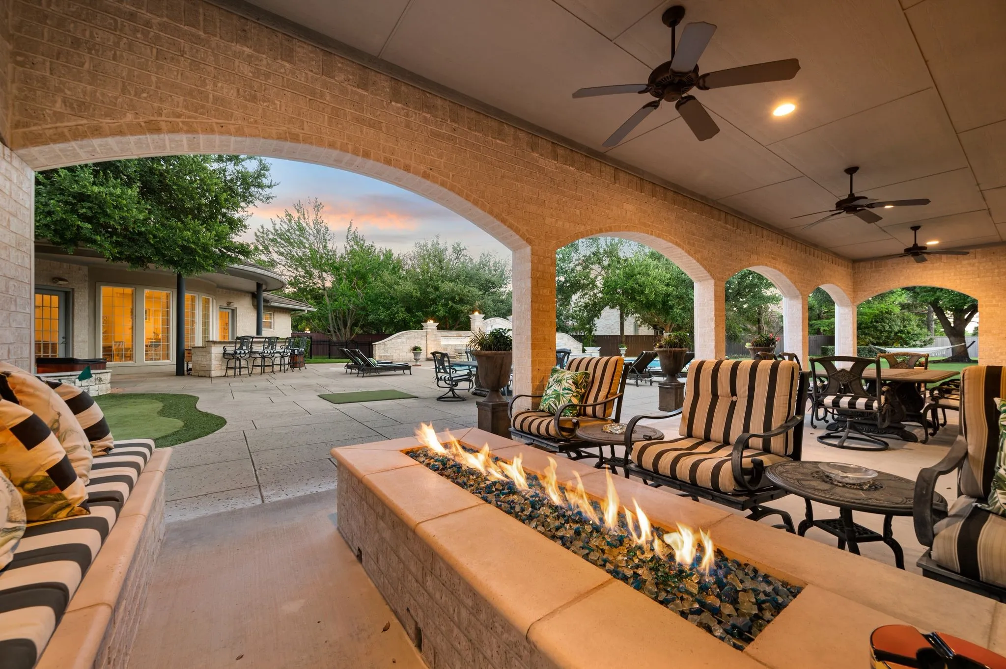 Expansive covered patio featuring a built-in fire pit, multiple ceiling fans, and recessed lighting