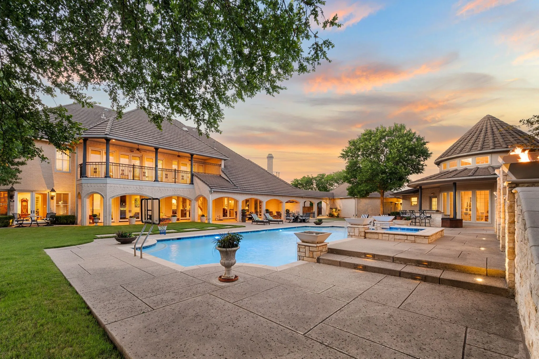 Expansive outdoor living area featuring a rectangular swimming pool, integrated spa, and spacious stone patio
