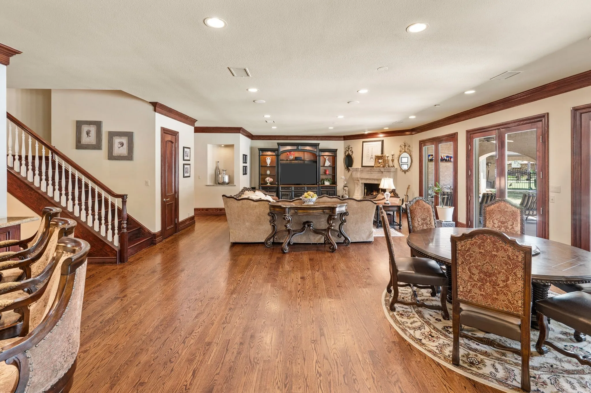 Spacious interior with wood-finish flooring, a grand staircase with white balusters, recessed lighting, and crown molding