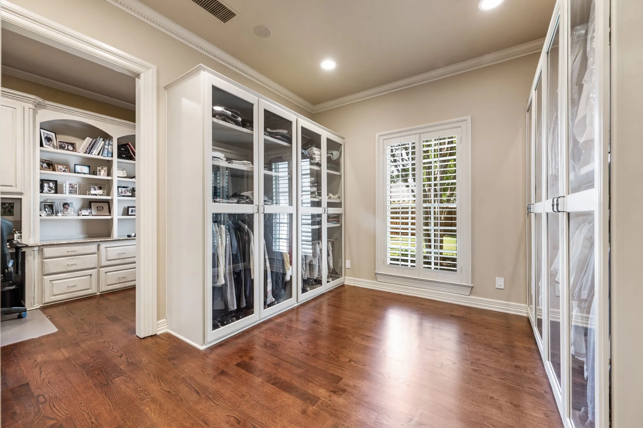 Hardwood-style flooring throughout this space with built-in cabinetry and glass-front wardrobes