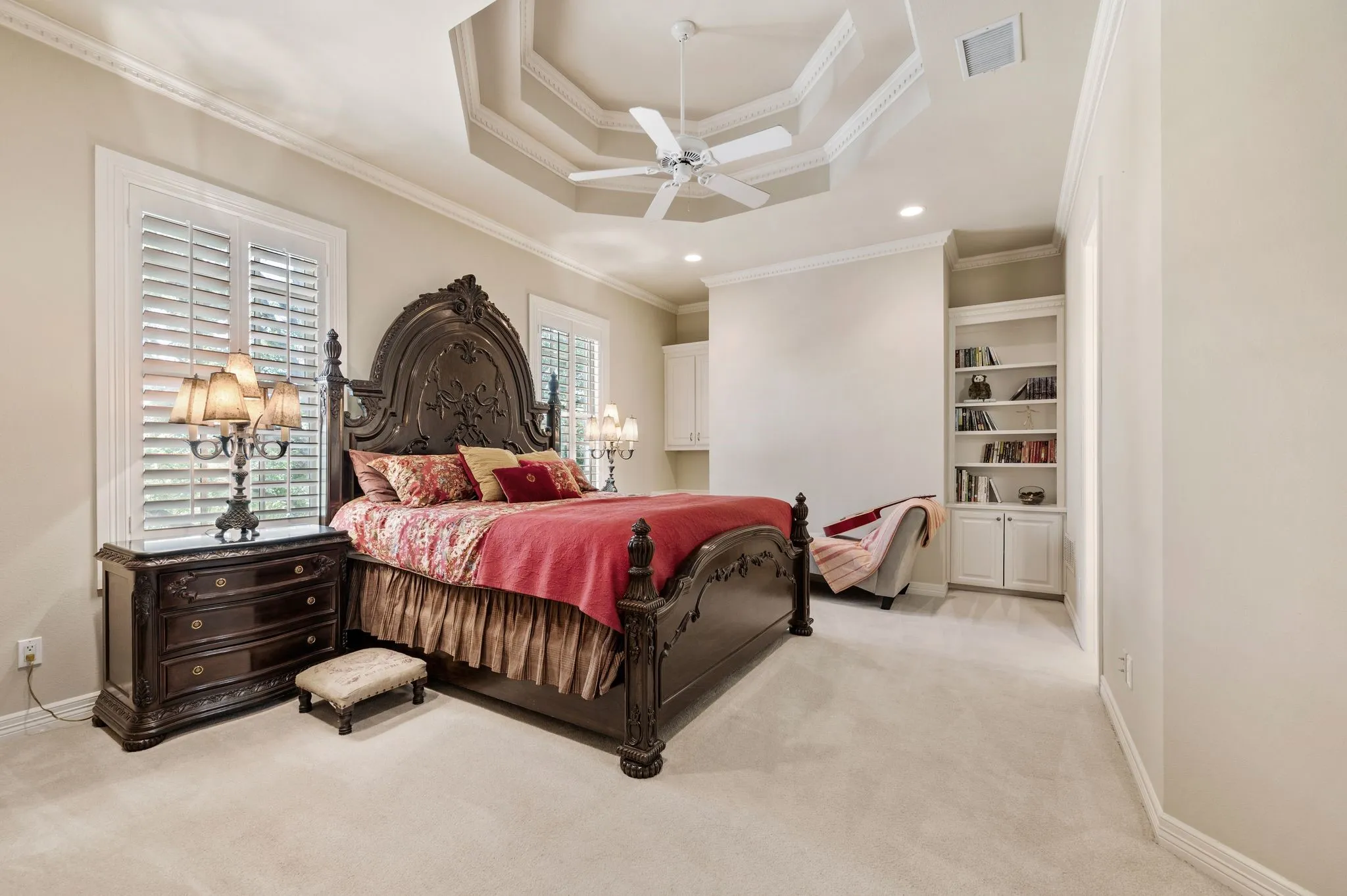 Recessed ceiling with layered trim, crown molding, and plantation shutters
