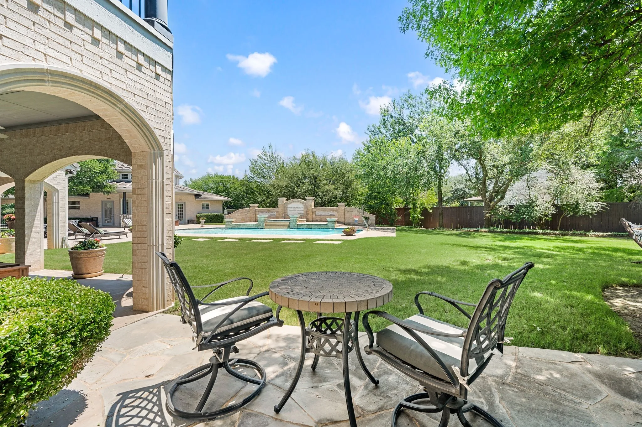 Stone patio with an arched covered area and a large grassy yard