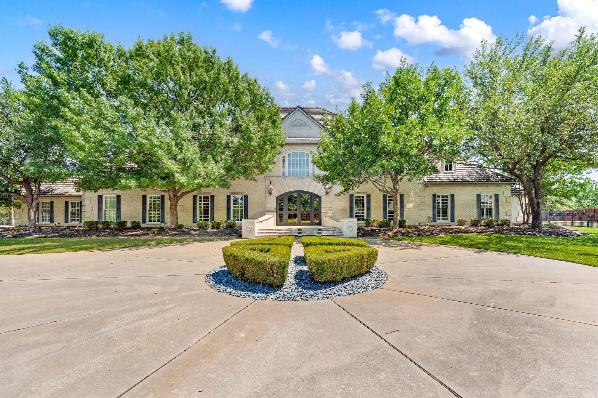 Stately light-colored brick exterior with dark shutters, featuring a grand arched entryway