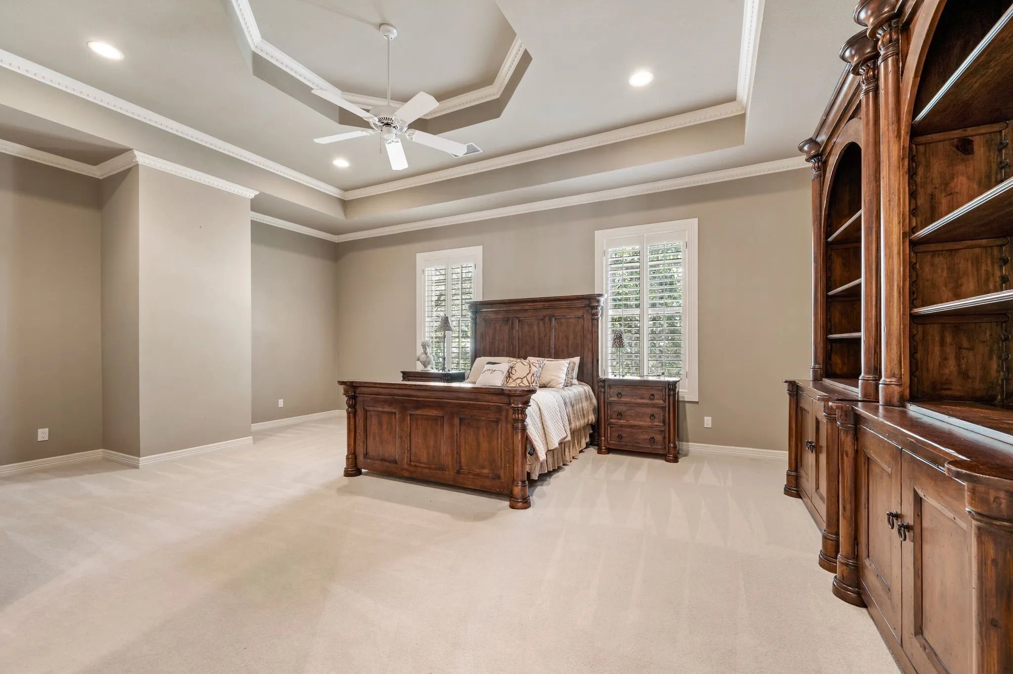 Spacious room with a tray ceiling and crown molding, featuring recessed lighting and a ceiling fan