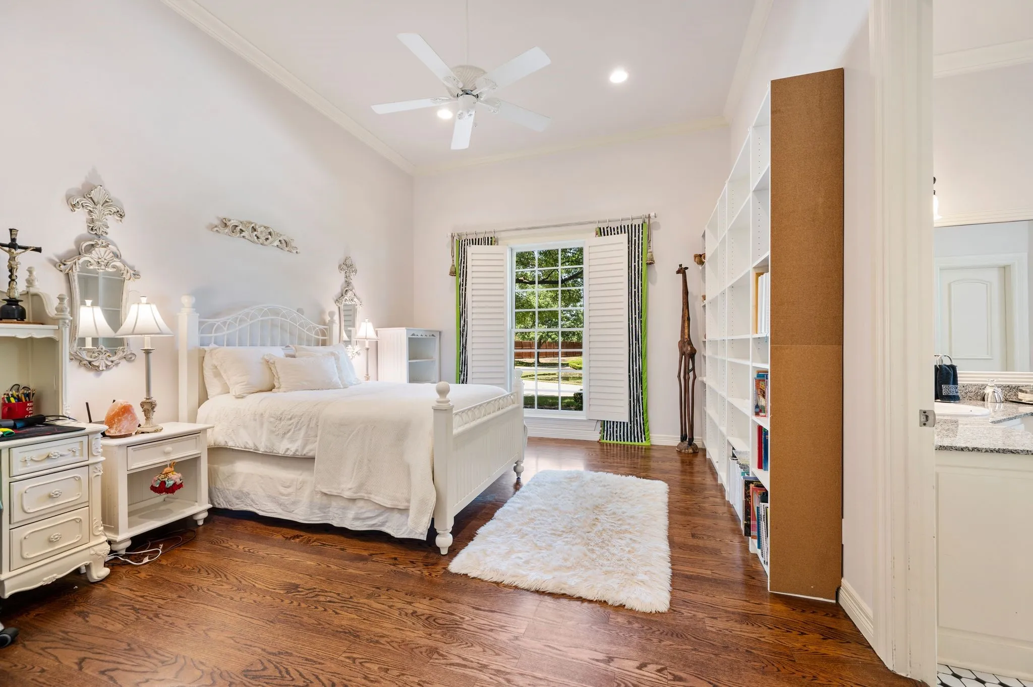 Bedroom featuring wood-finish flooring, a vaulted ceiling, and an expansive window with plantation shutters