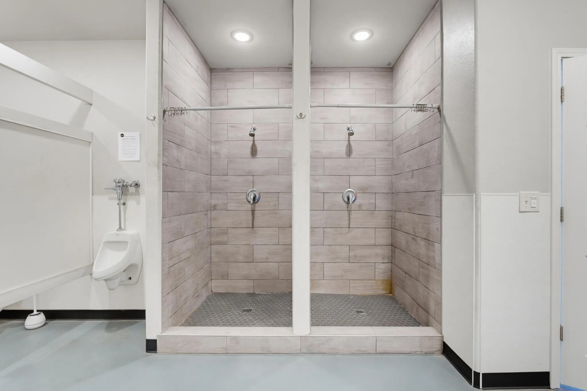 Two individual shower stalls featuring tiled walls and metal shower fixtures