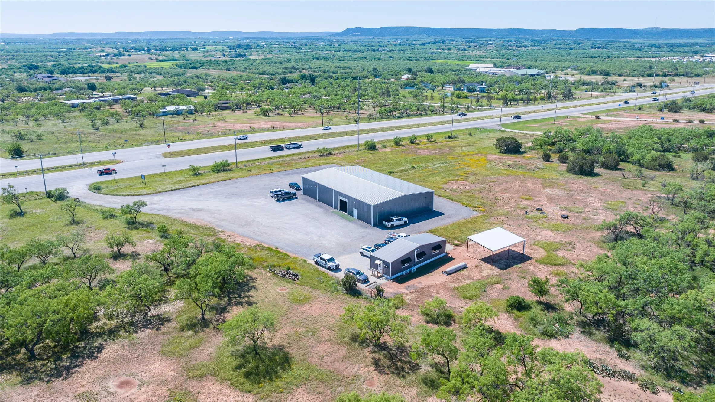 Commercial property featuring a large metal building, a smaller modular building, and an open-sided carport structure