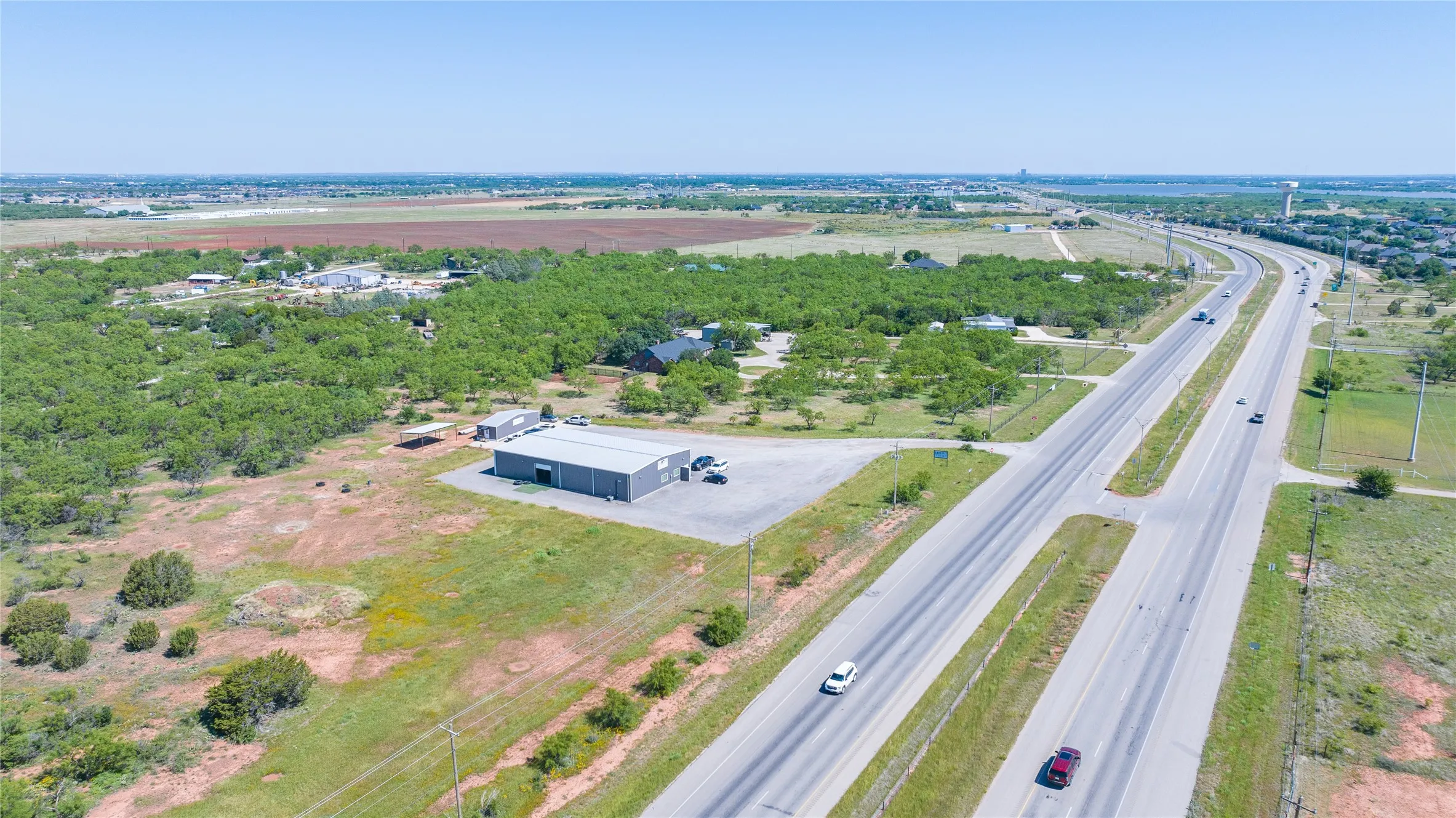 Expansive property featuring a multi-lane highway, substantial commercial building, and a broad, undeveloped land parcel