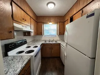 U-shaped kitchen featuring wood cabinetry, light-toned countertops, and a white tile backsplash