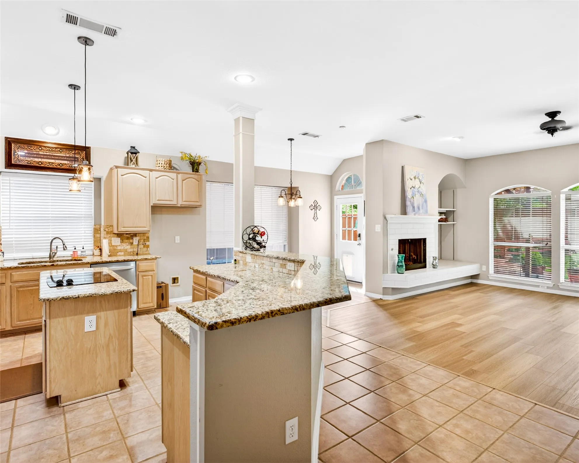Spacious open-concept interior featuring a kitchen with light wood cabinetry, granite countertops, and a tile backsplash