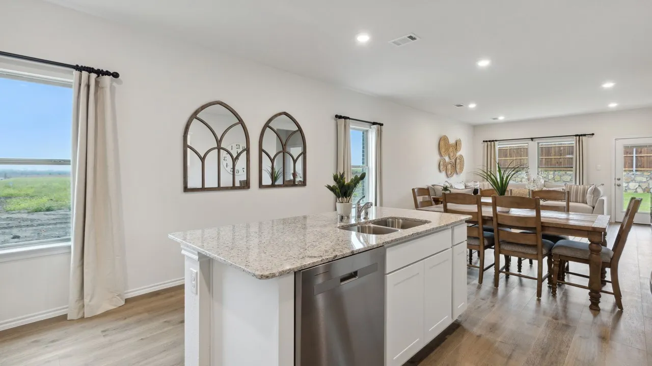 Kitchen island featuring a double-basin stainless steel sink, white cabinetry, and a light-toned speckled countertop