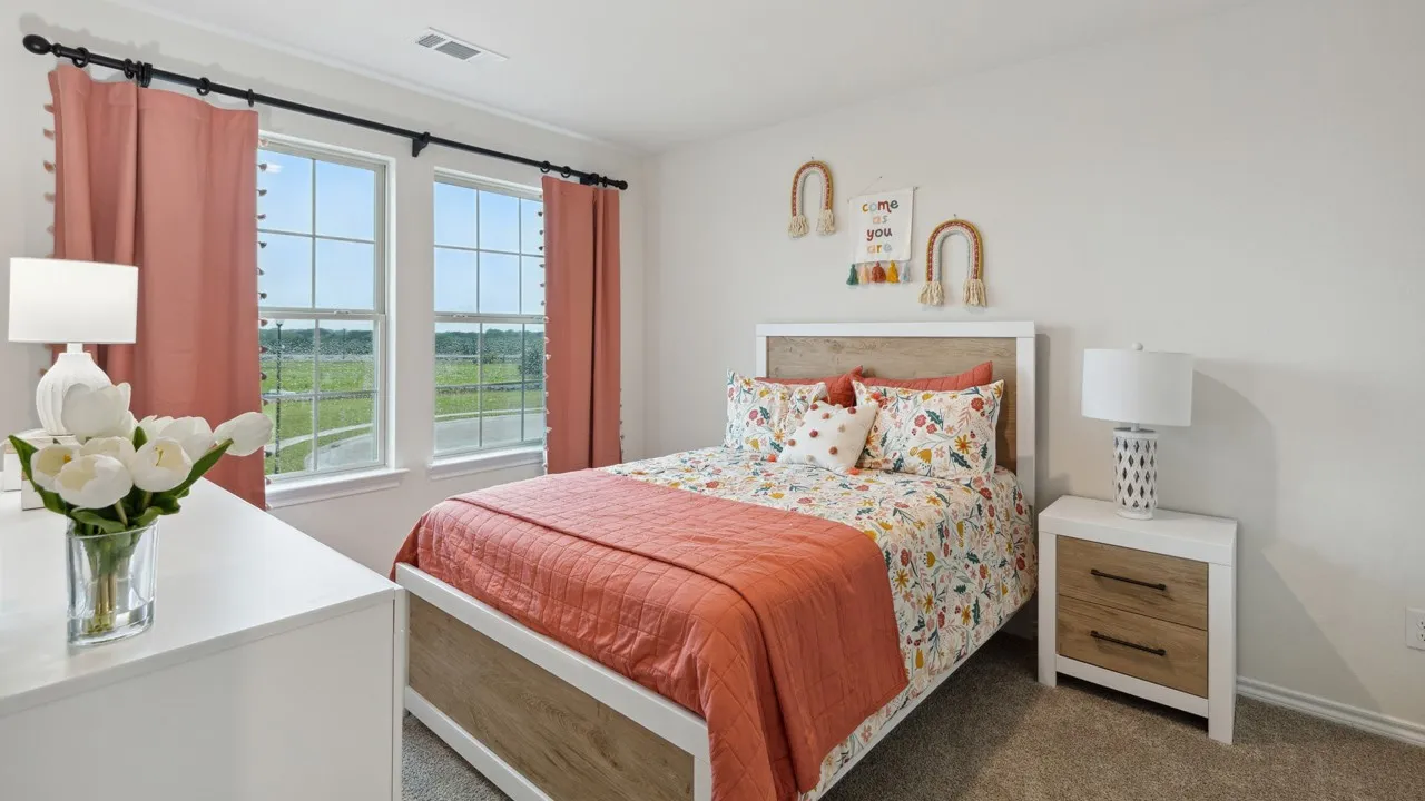 Bedroom featuring two large windows with grid patterns, light-colored walls, and neutral carpeting